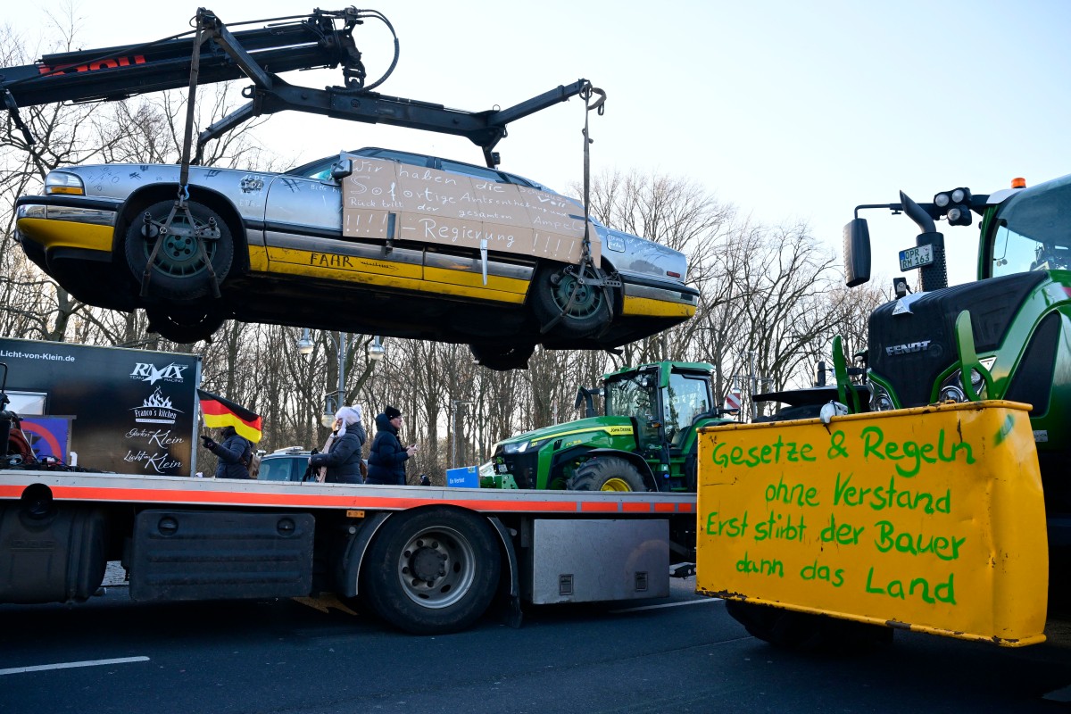 Anti-government slogans are written on a car hanging from a vehicle transporter during a protest against the federal government's austerity plans in Berlin