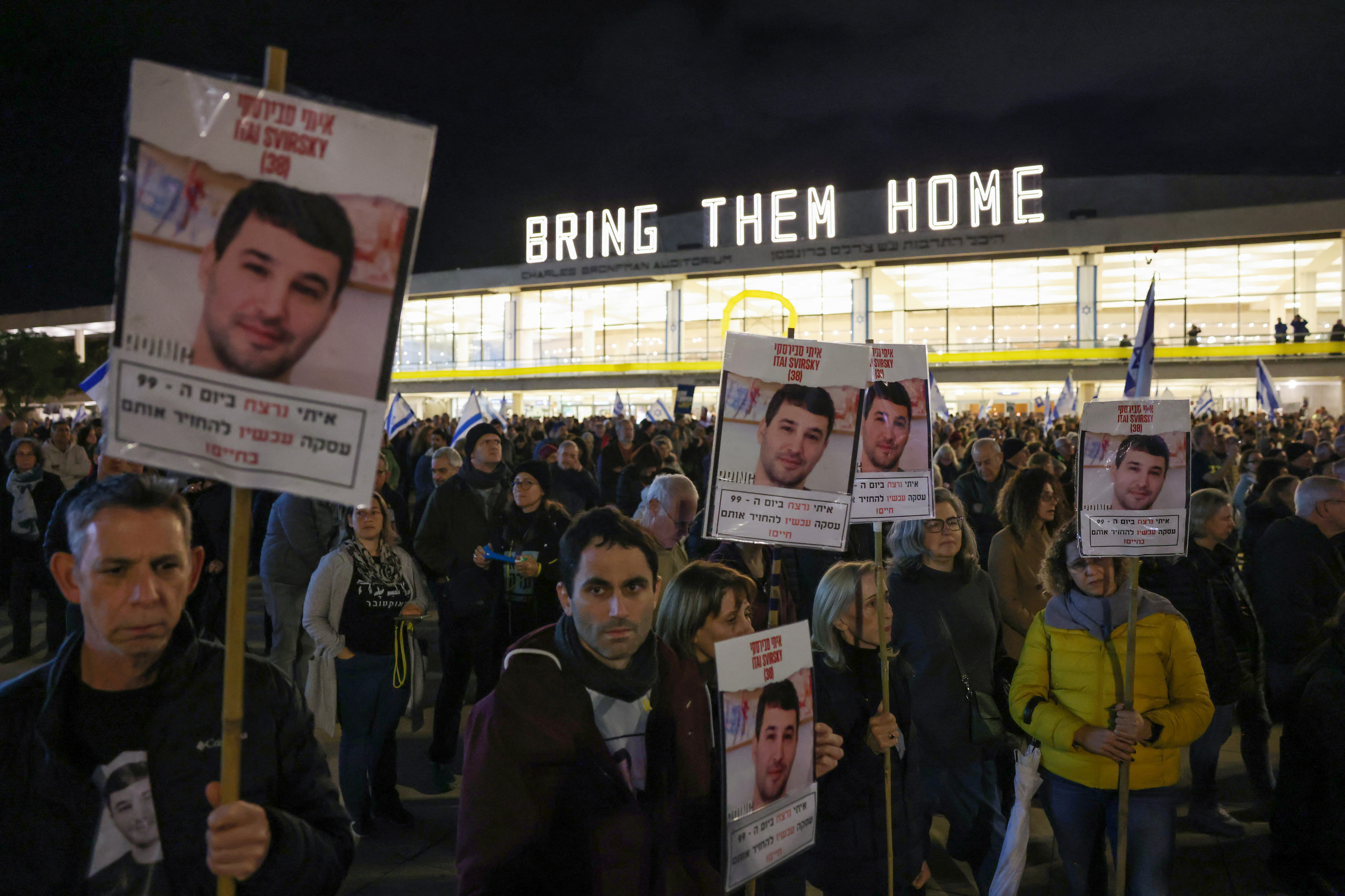 Protesters lift portraits of Itay Svirsky held hostage by Palestinian Hamas militants since October 7, during a rally in Israel's central city of Tel Aviv on January 27