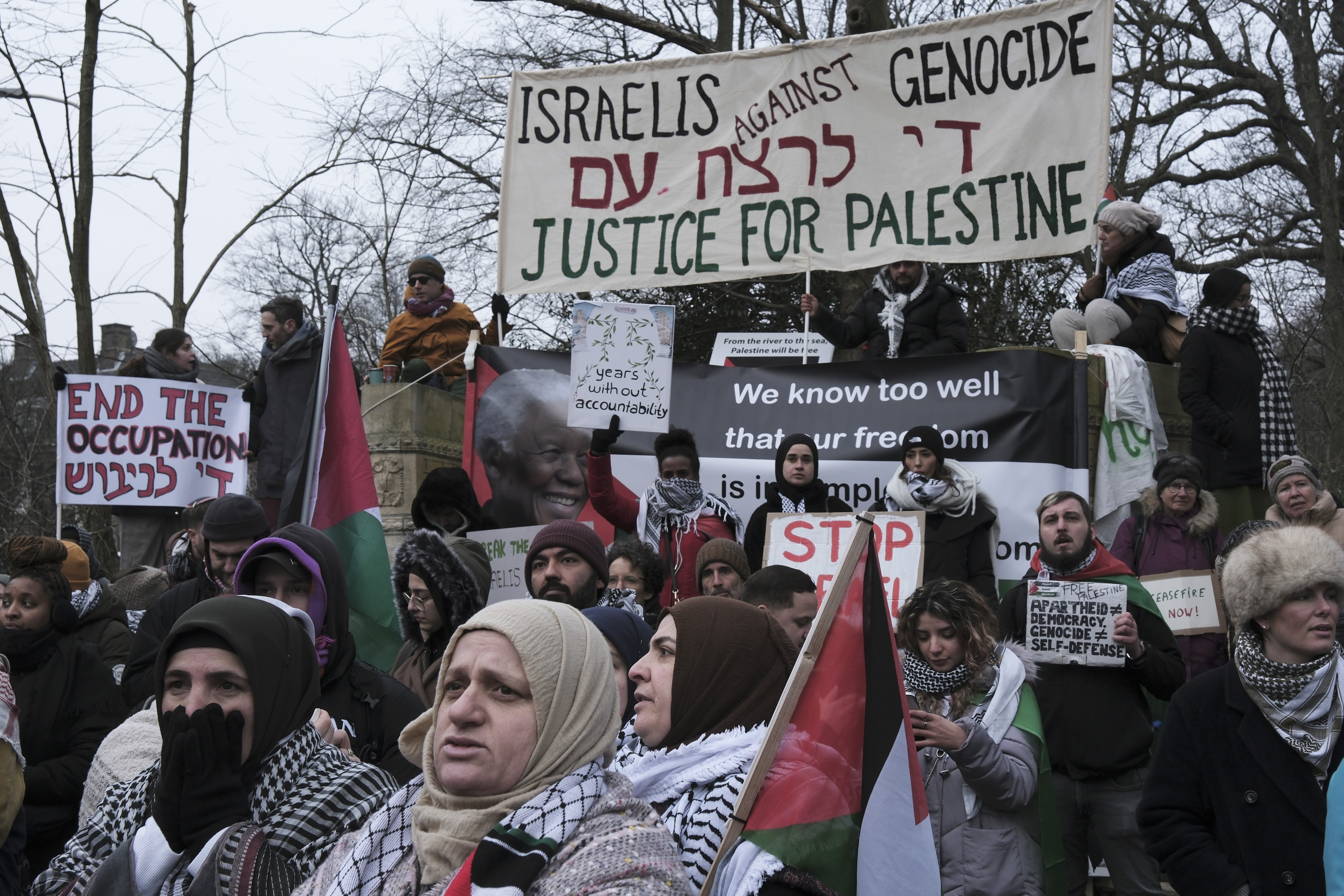 Protestors hold signs and wave Palestinian flags during a demonstration march outside the International Court of Justice in The Hague, Netherlands