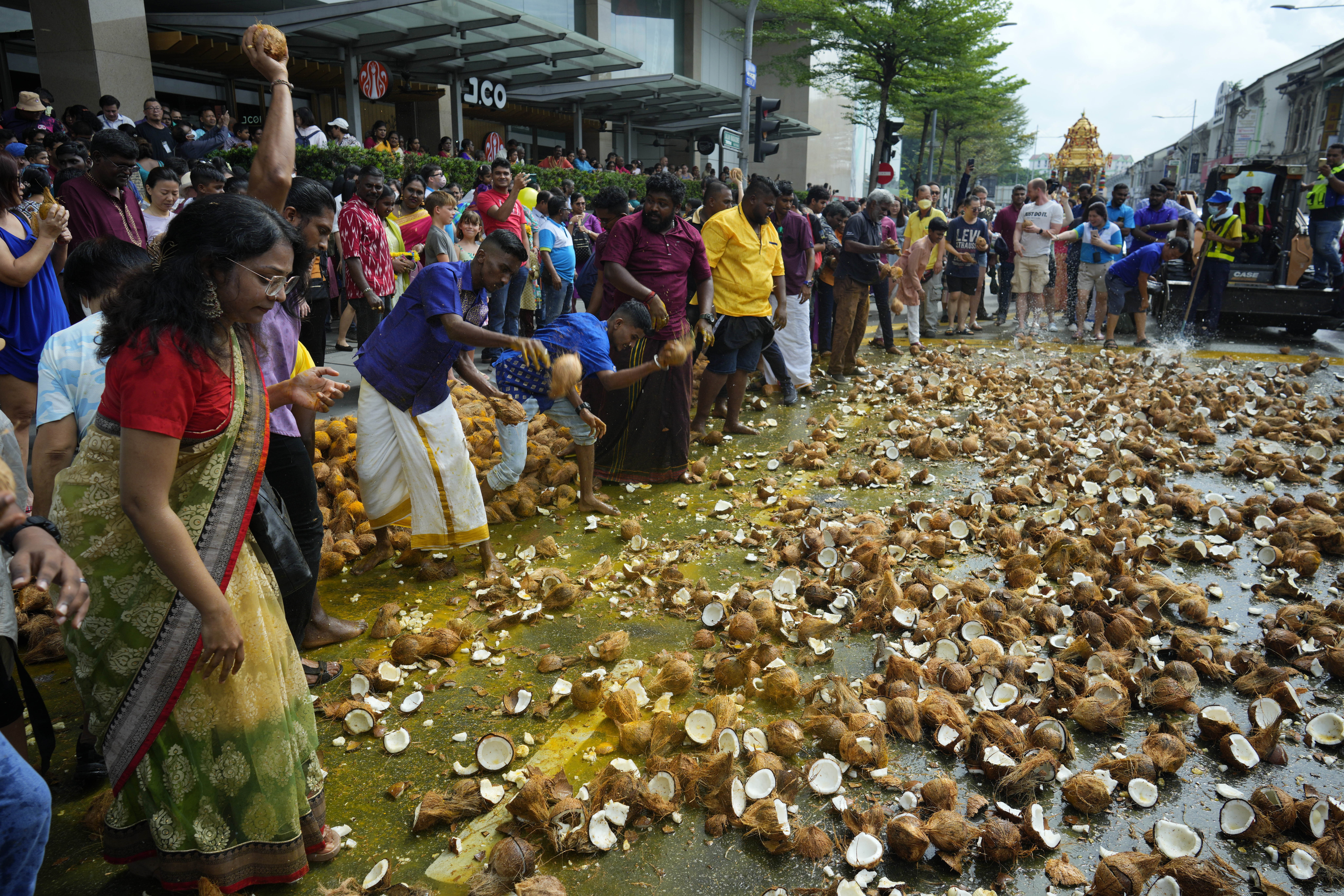 People smashing coconuts on the ground along a street in Penang