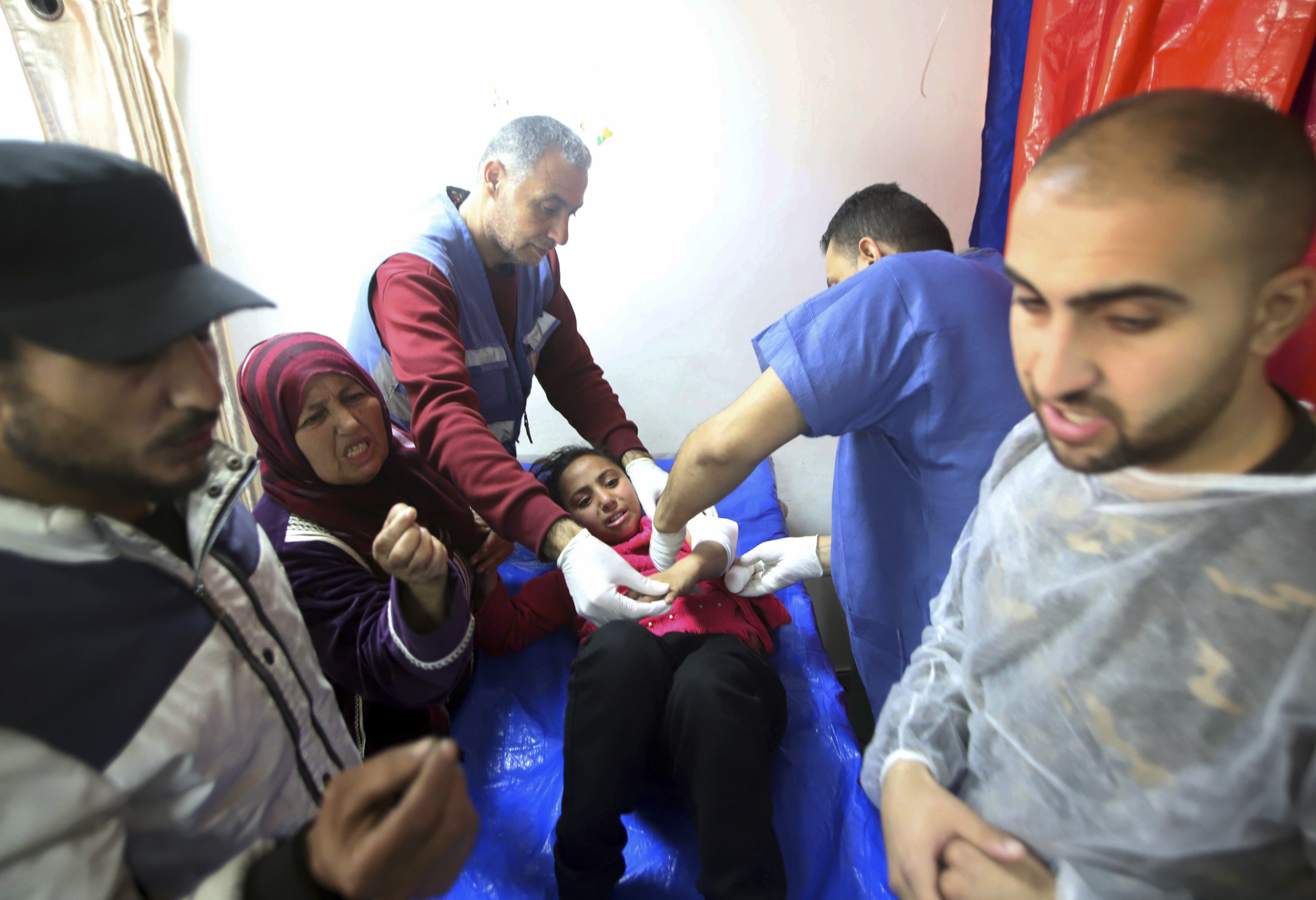 Palestinian medics treat a girl wounded in the Israeli bombardment at a building of an UNRWA vocational training center which displaced people use as a shelter in Khan Younis, southern Gaza Strip