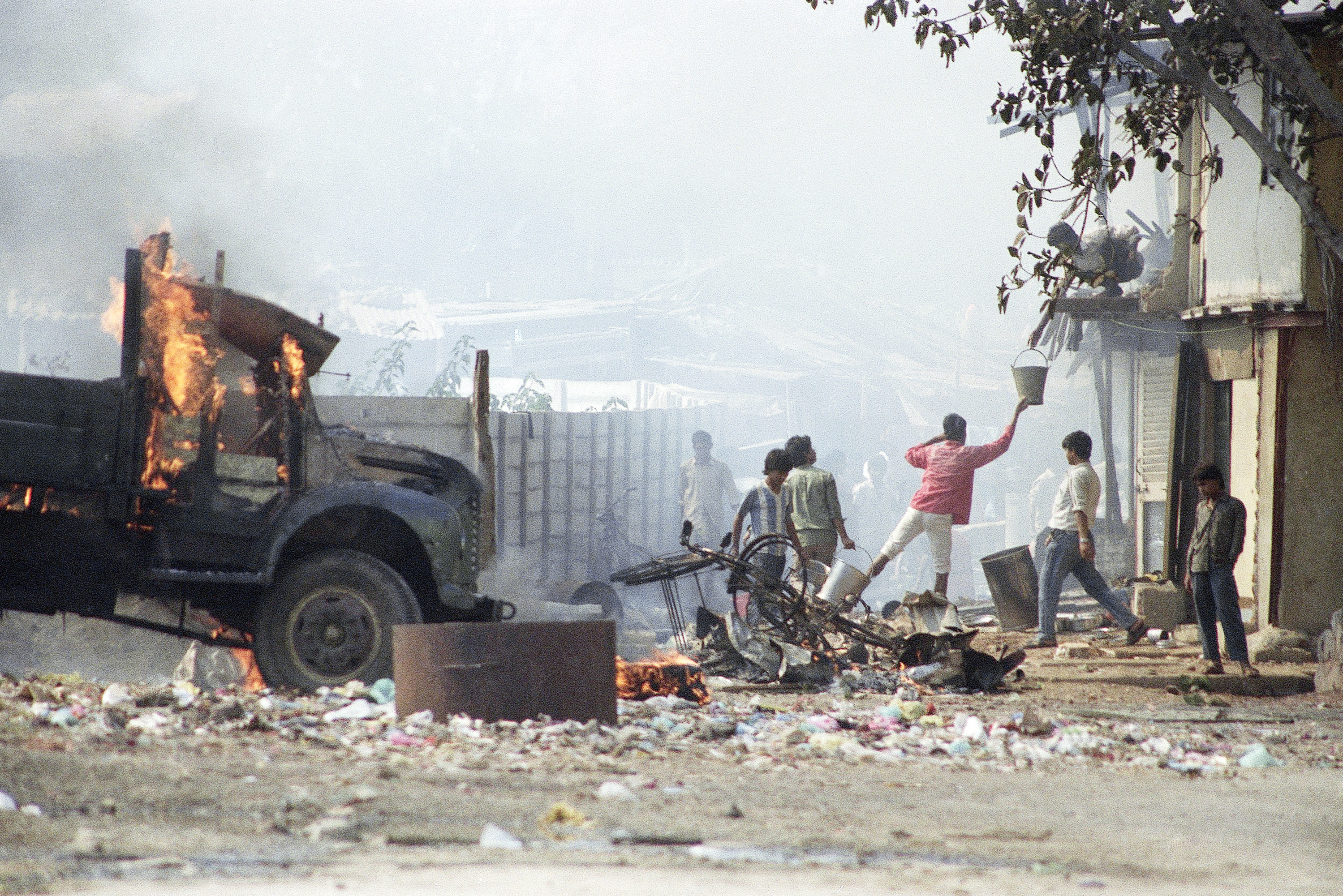 Residents pass water buckets in an effort to put out fires after riots in Bombay, Wednesday, Jan. 13, 1993. Four people were stabbed on Wednesday in Hindu-Muslim violence that has left nearly 500 people dead in eight days of rioting, news reports said. (AP Photo/Ajit Kumar)