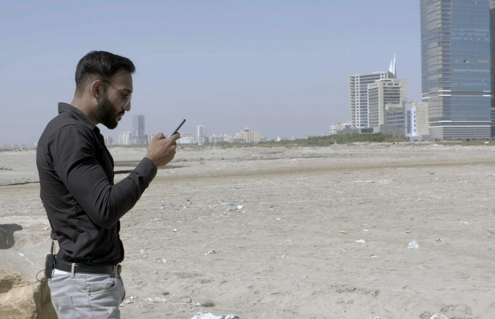 A man stands on a Karachi beach holding his mobile phone