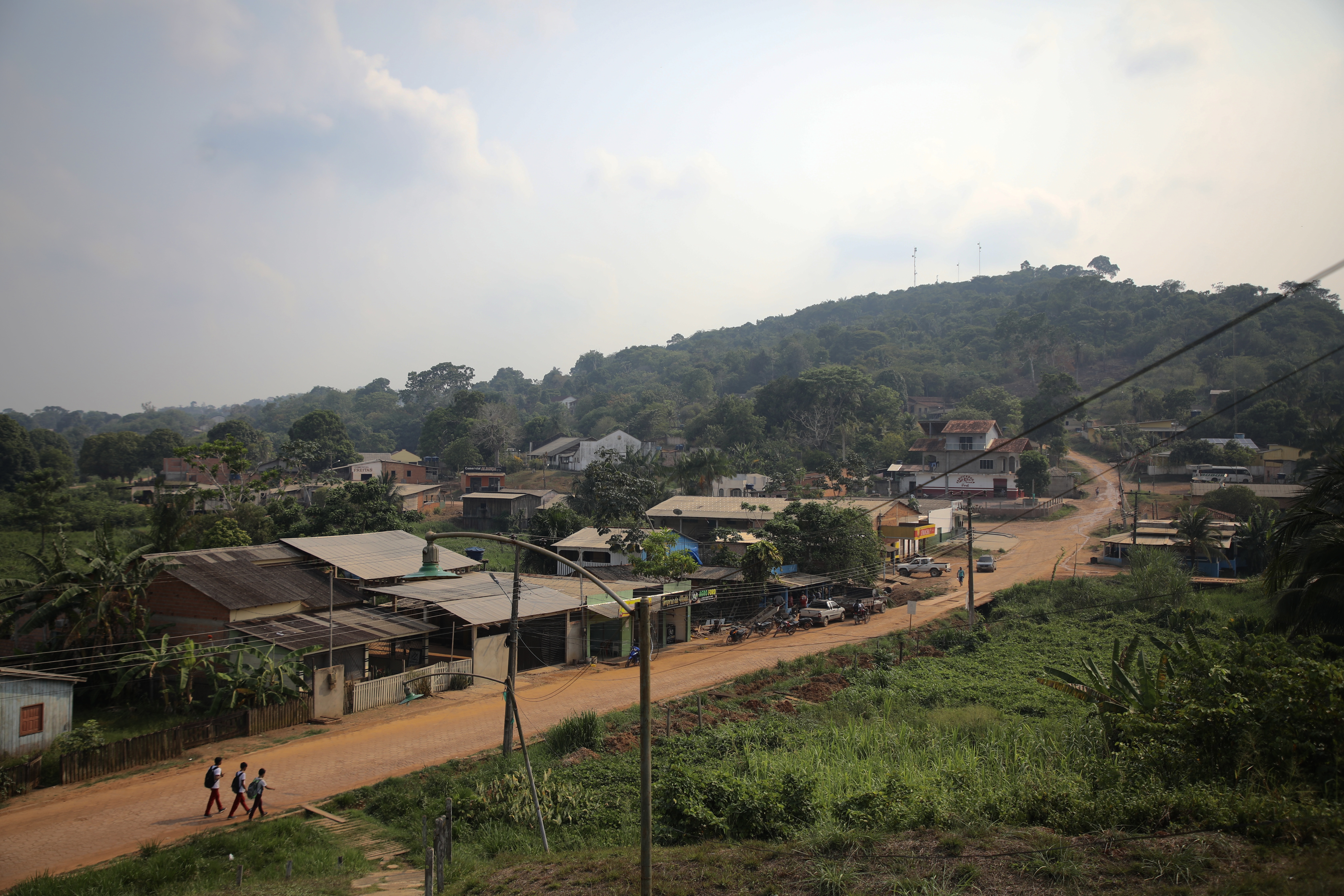 A dirt road, lined with modest homes, runs through the Amazon rainforest.