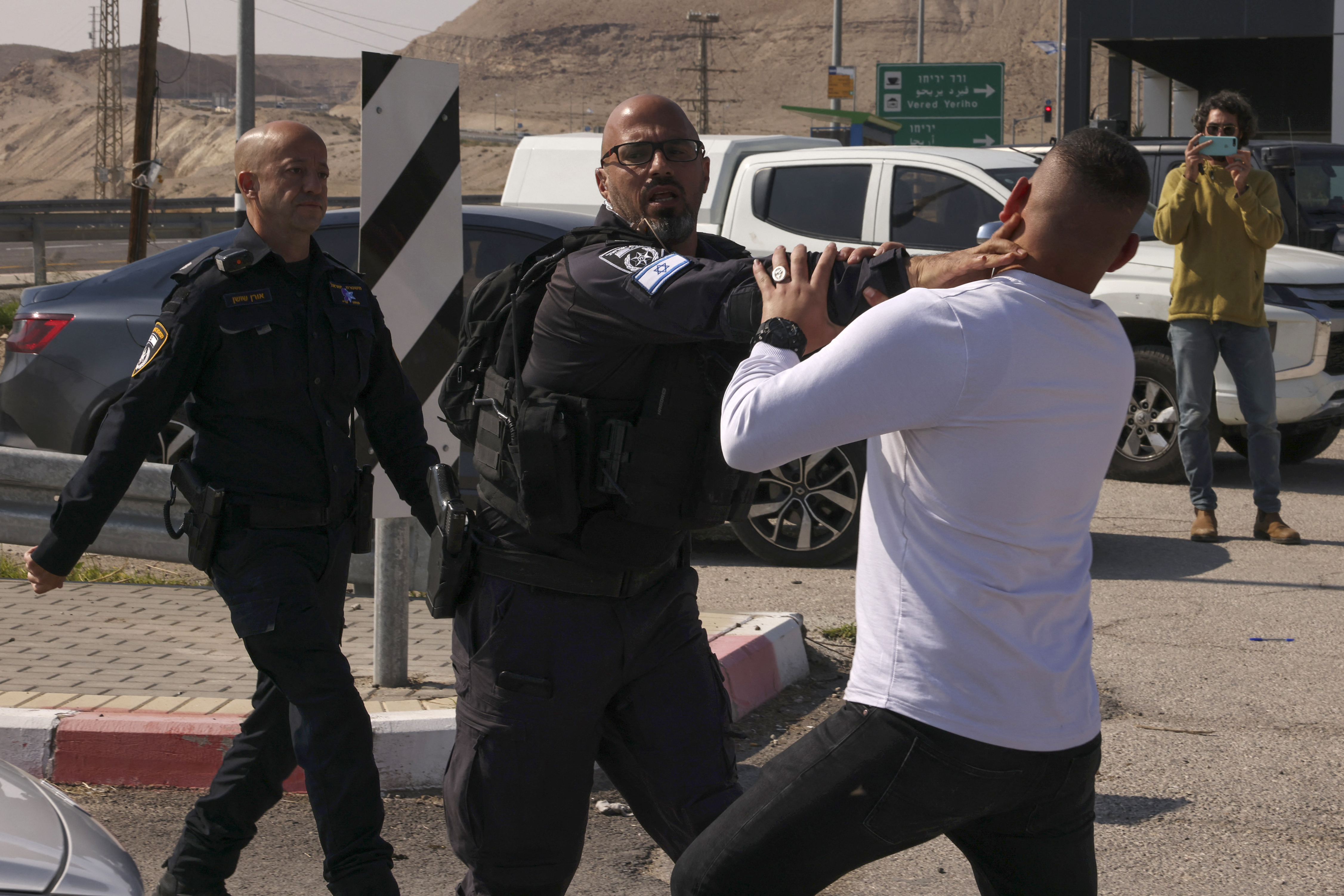 Members of Israeli security forces arrest a demonstrator as Israeli and Palestinian activists protest Israel's ongoing war in Gaza, at a junction leading to Jericho city in the occupied West Bank on February 9, 2024. (Photo by HAZEM BADER / AFP)