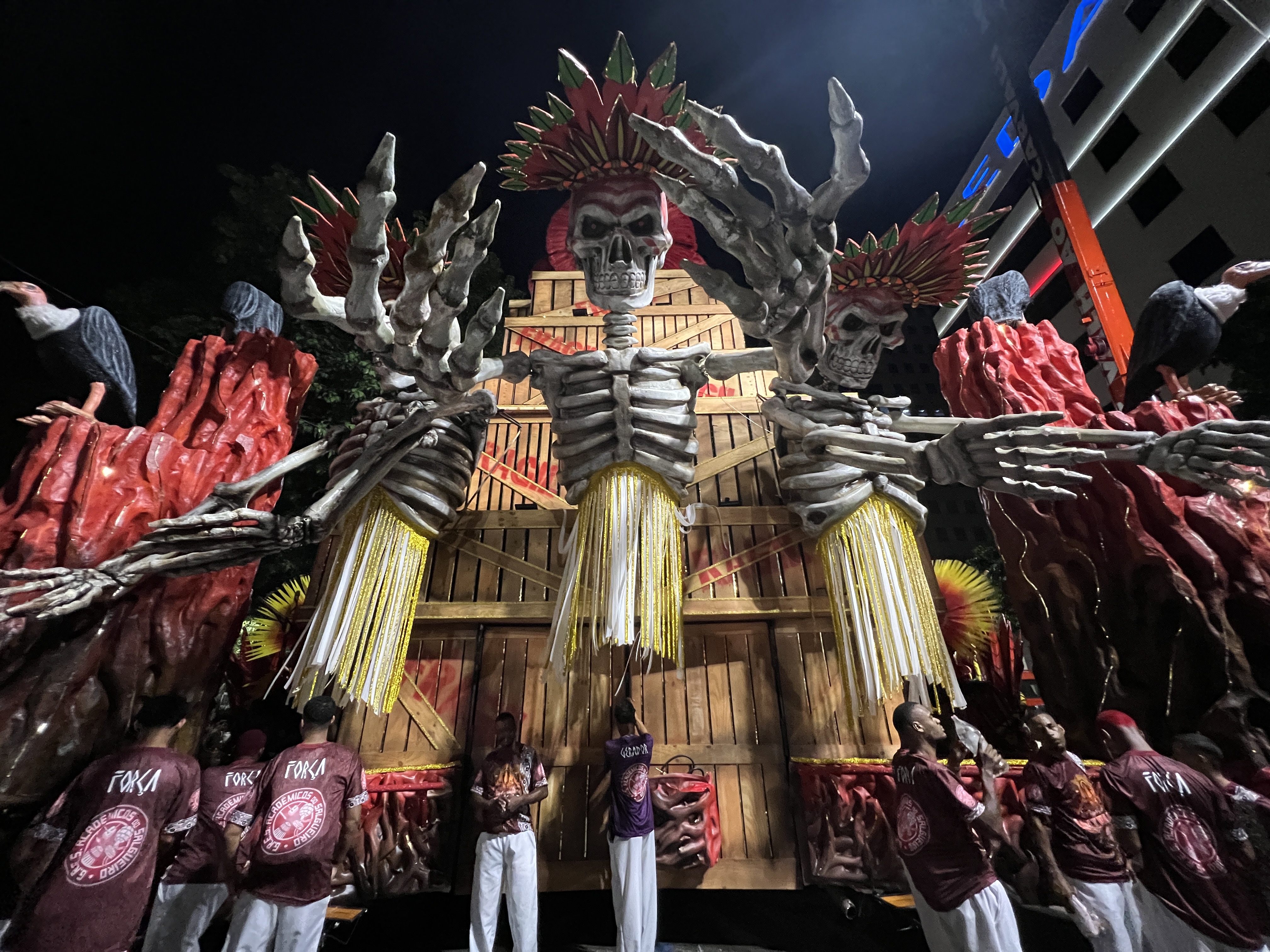 A parade float at the Sambadrome shows three skeletons with Indigenous-style feathered headdresses, to symbolize the destruction wrought by mining activity.