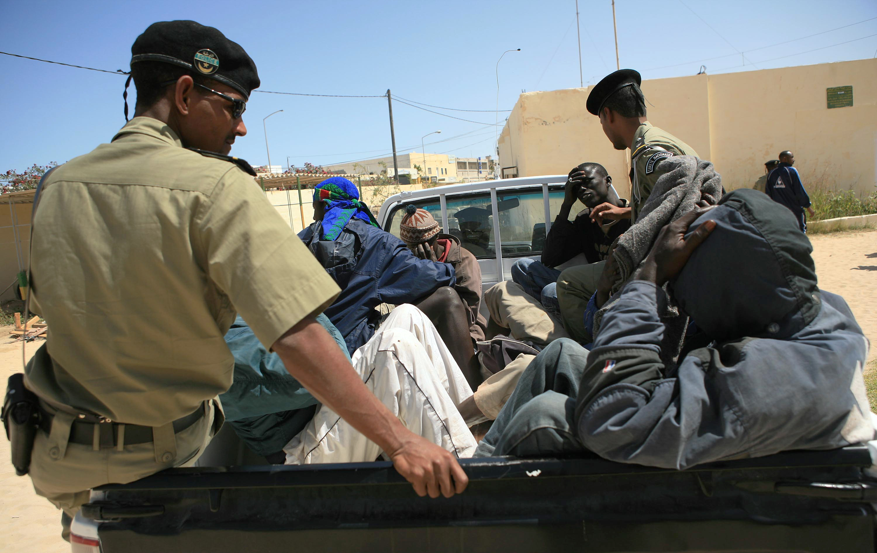 Would-be immigrants are transported in a car by Mauritanian police officials in Nouadhibou before being expelled from the country May 23, 2006. As Spain has improved cooperation with Morocco and Mauritania to close down clandestine migration routes, both on land and sea, would-be migrants have been setting off from further and further down the West African coast. REUTERS/Juan Medina