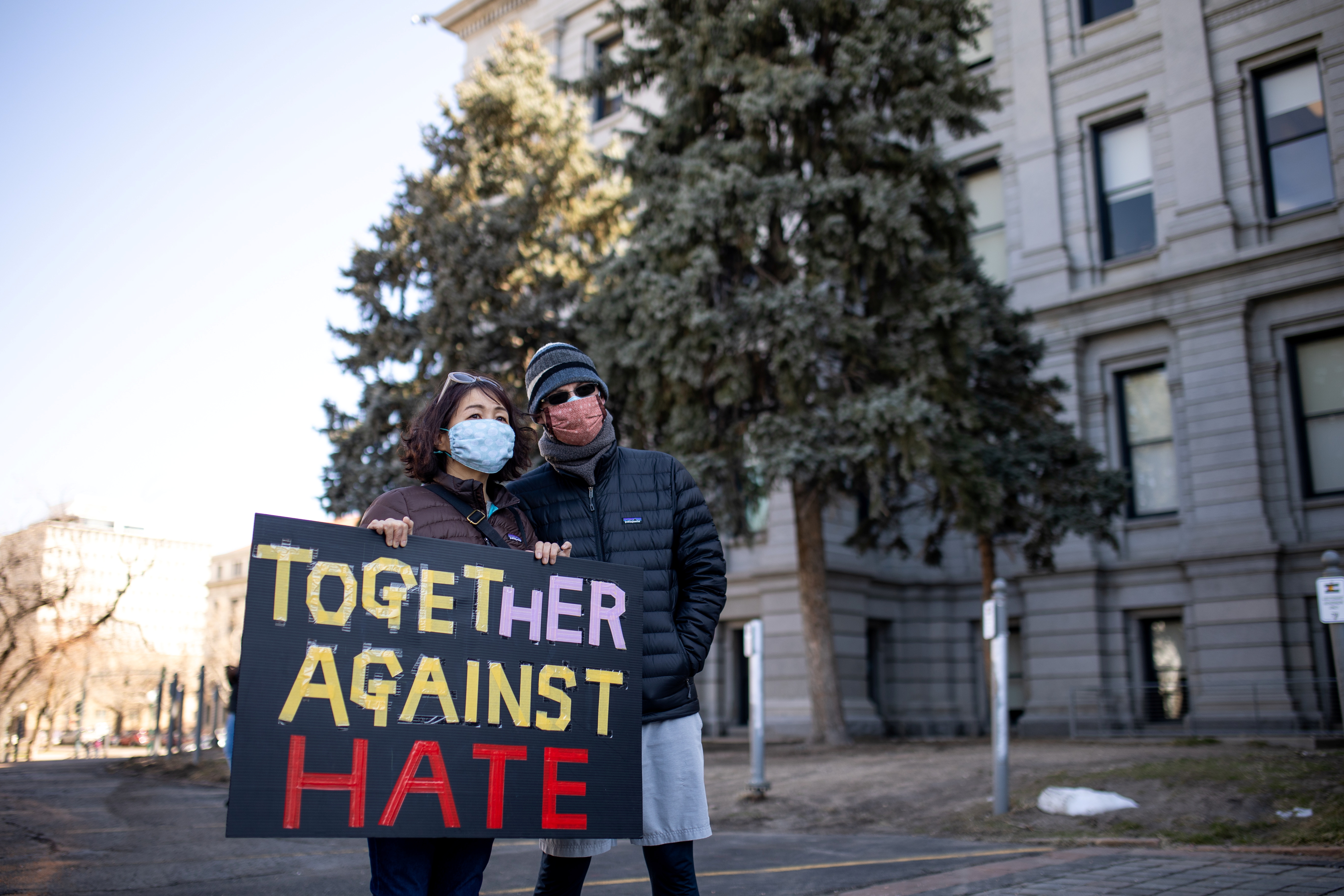 A woman holds a sign that reads 'Together Against Hate' during a wave of anti-Asian hate during the COVID-19 pandemic