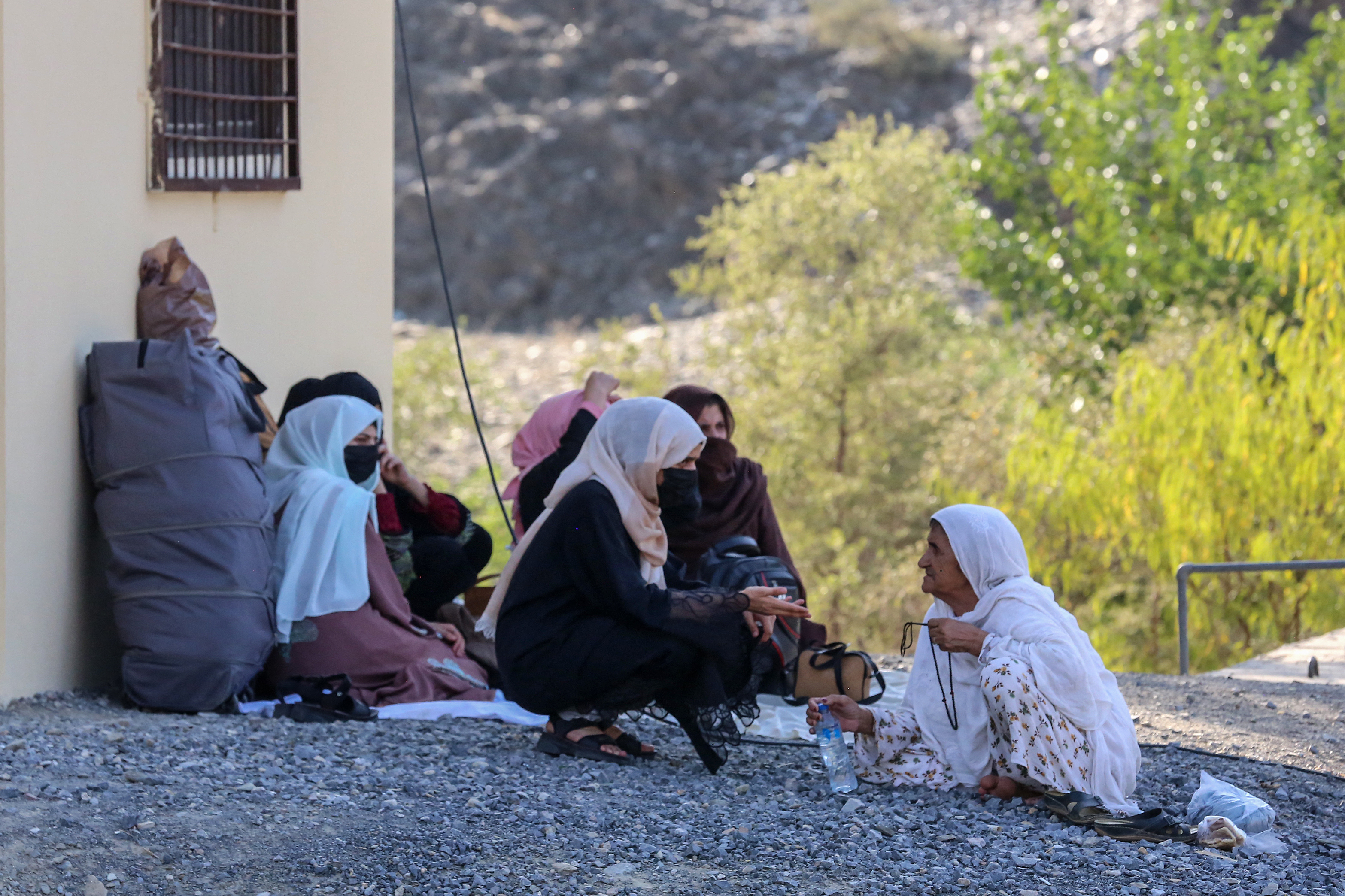 Afghan women sit along a road as they wait for the reopening of Torkham International Border crossing in Torkham of Nangarhar province on September 11, 2023, following a gun battle between Pakistan and Afghan border forces. - A gun battle erupted September 6 between Pakistan and Afghan border forces, officials said, with each side blaming the other for starting the firefight that shut their busiest trade crossing. (Photo by Shafiullah KAKAR / AFP)