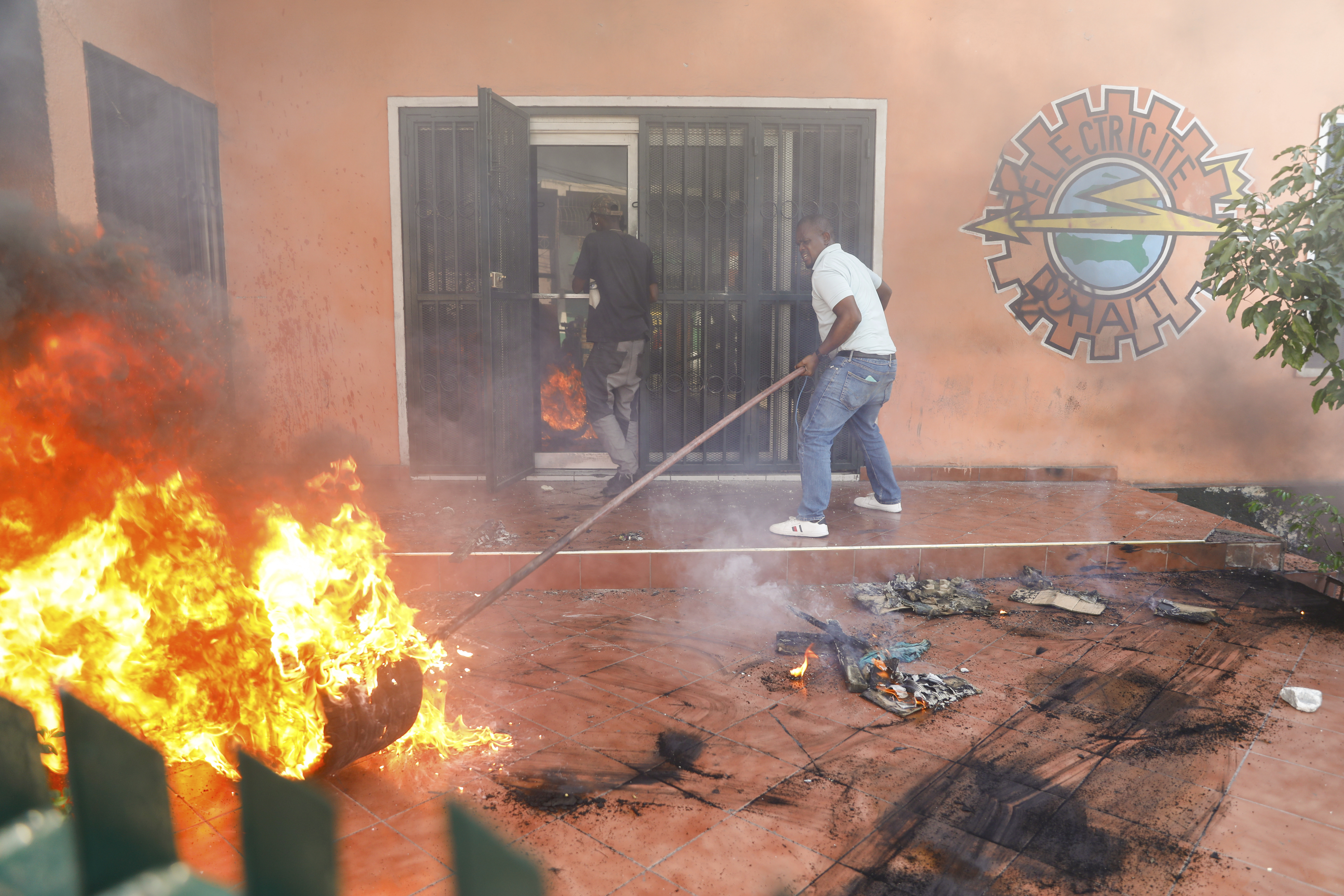 Workers put down a fire set at an office of Haiti's power company during a protest to demand the resignation of Prime Minister Ariel Henry