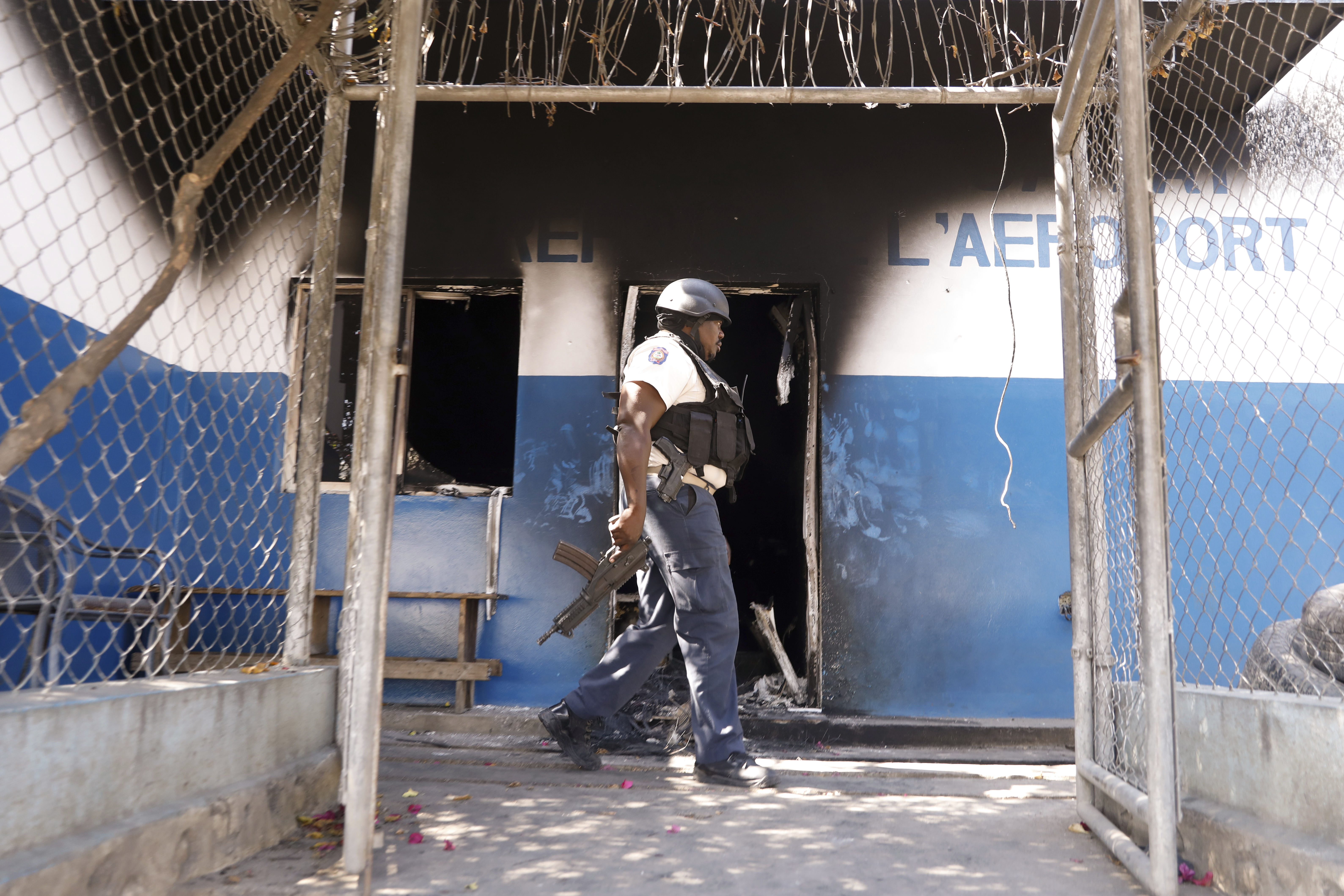 A police officer walks at a police station set on fire by armed gangs in Port-au-Prince, Haiti