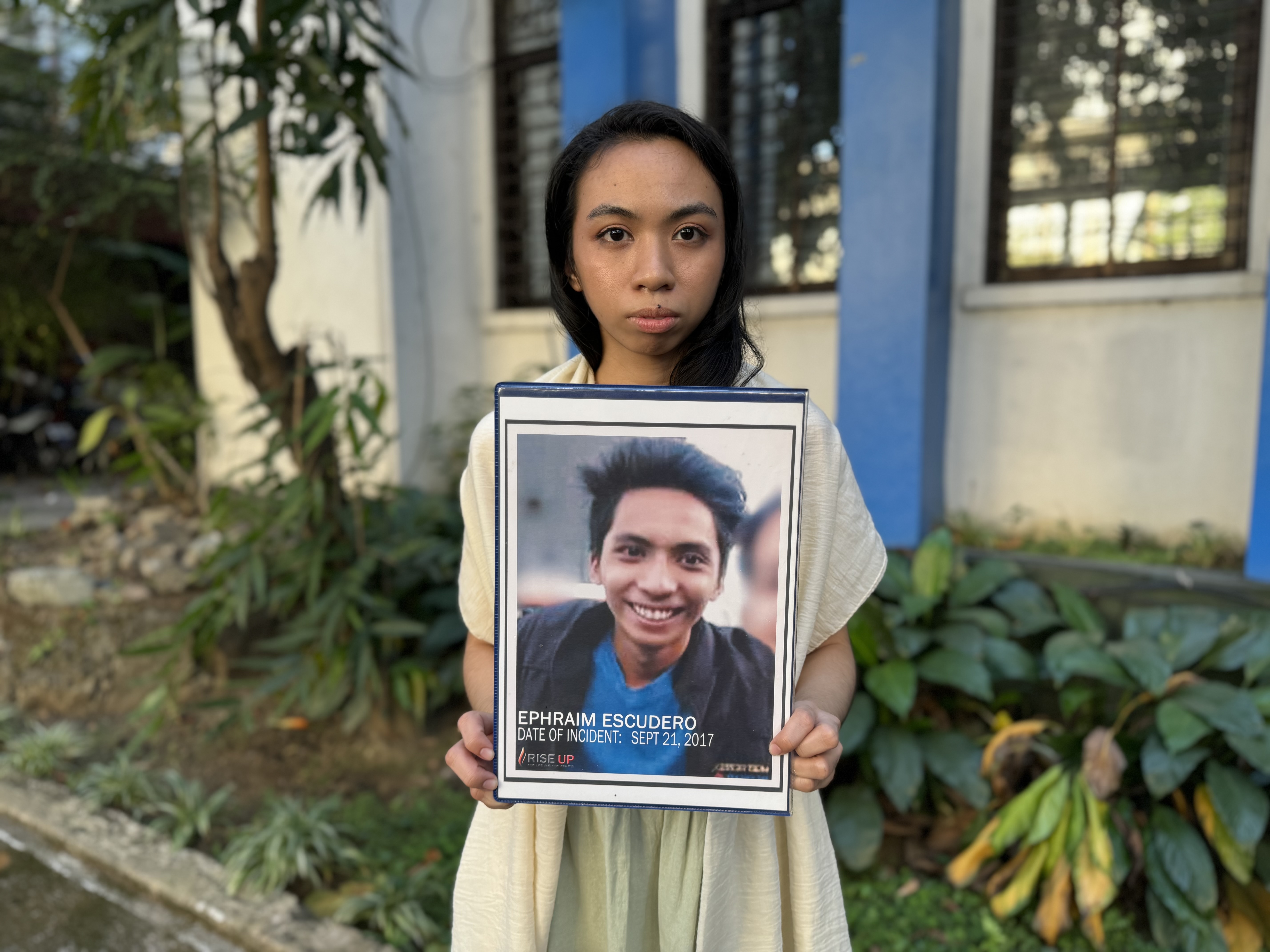 Sheerah Escudero holding a photo of her brother