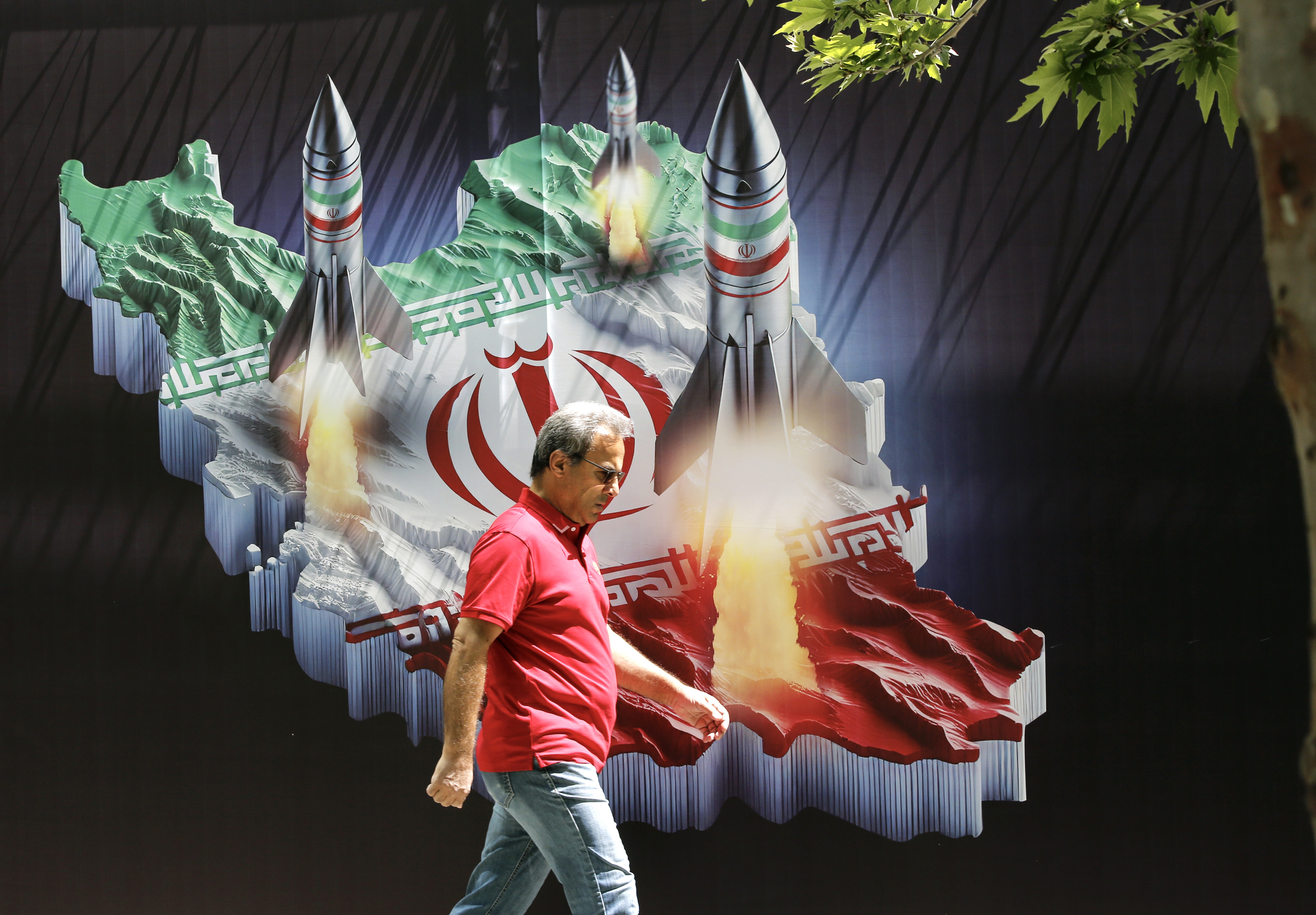 An Iranian man walks past a huge anti-Israeli banner