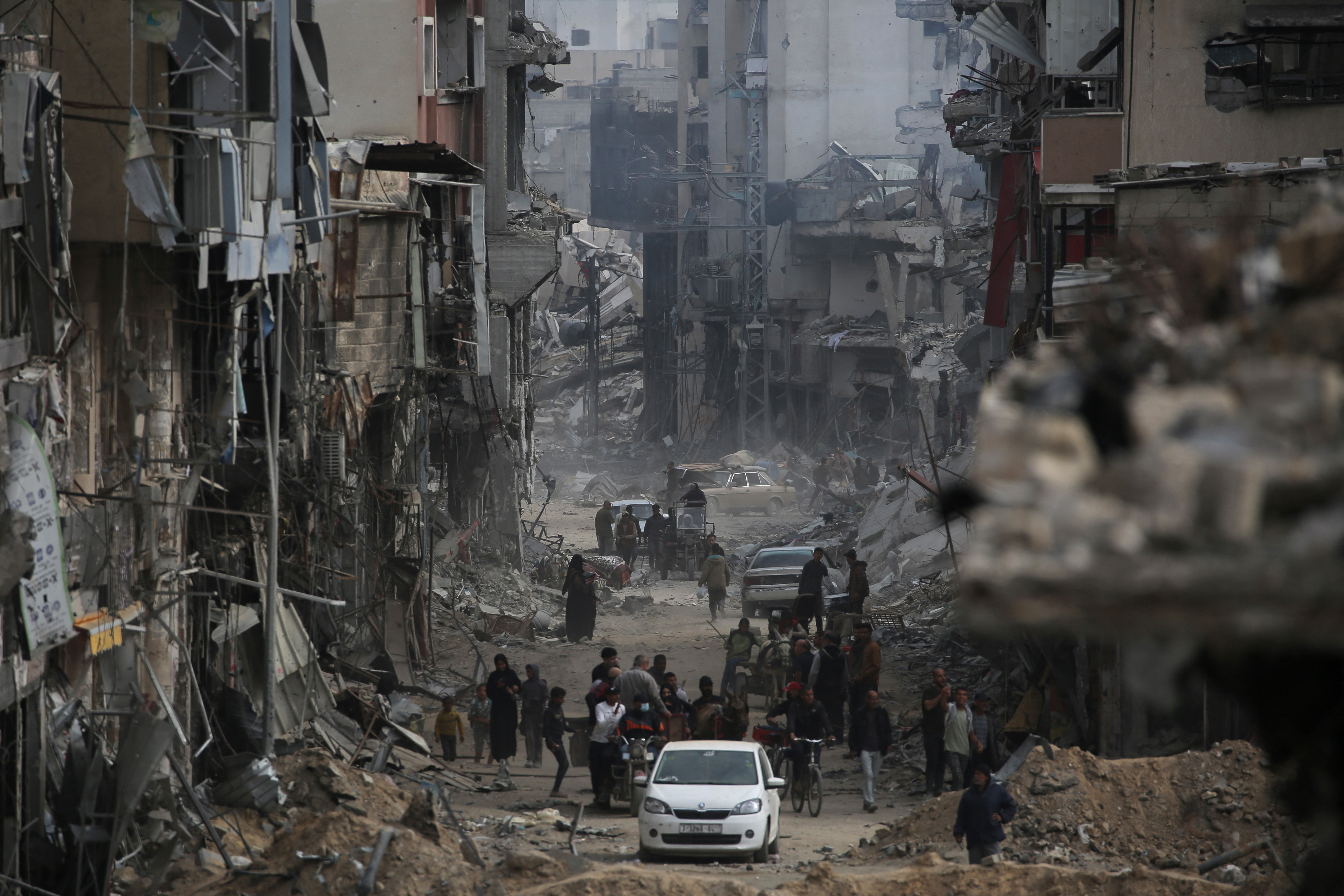 Palestinians walk past damaged buildings in Khan Younis on April 8