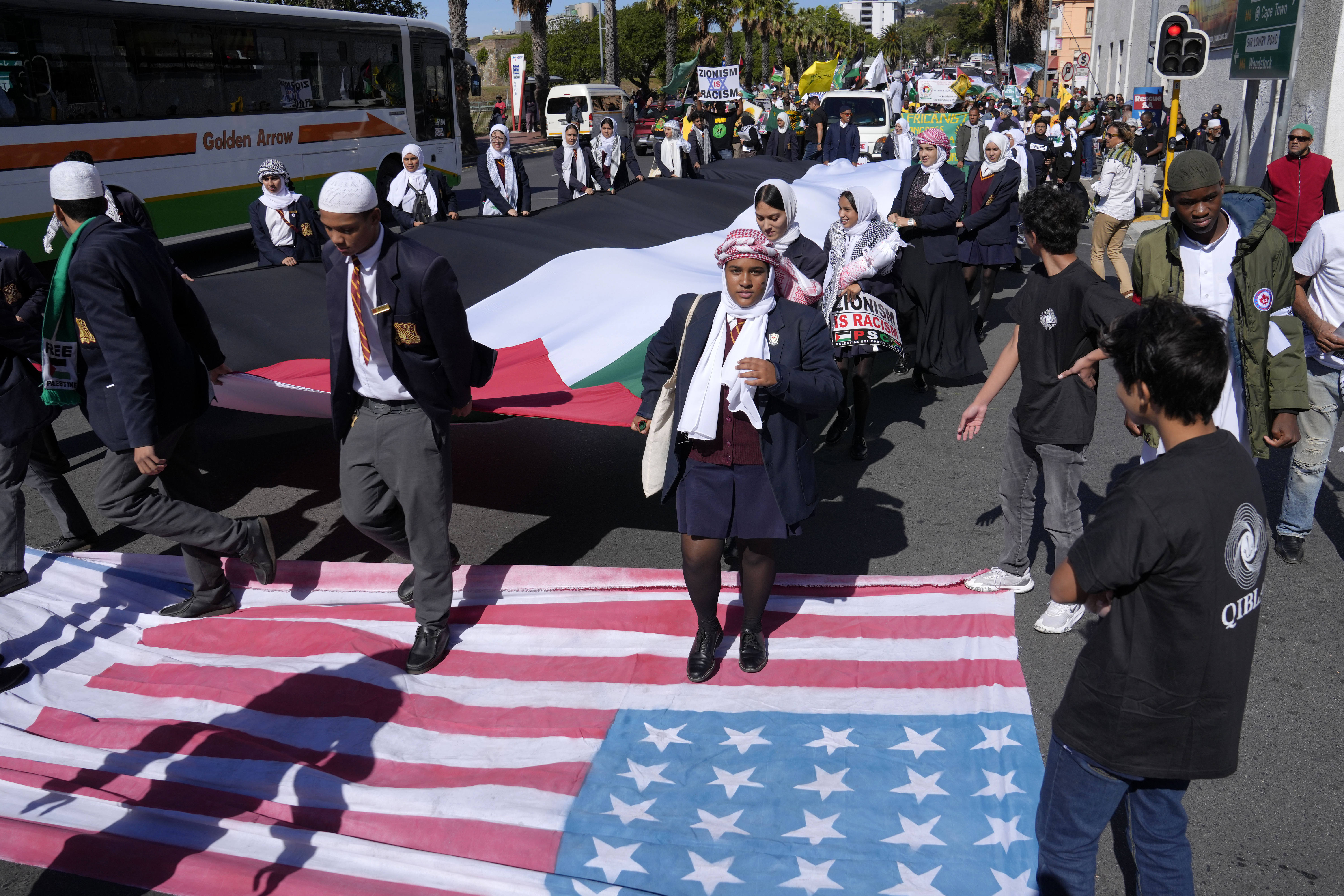 Pro-Palestinian supporters walk over American and Israeli flags as they take part in a Quds Day protest in Cape Town, South Africa