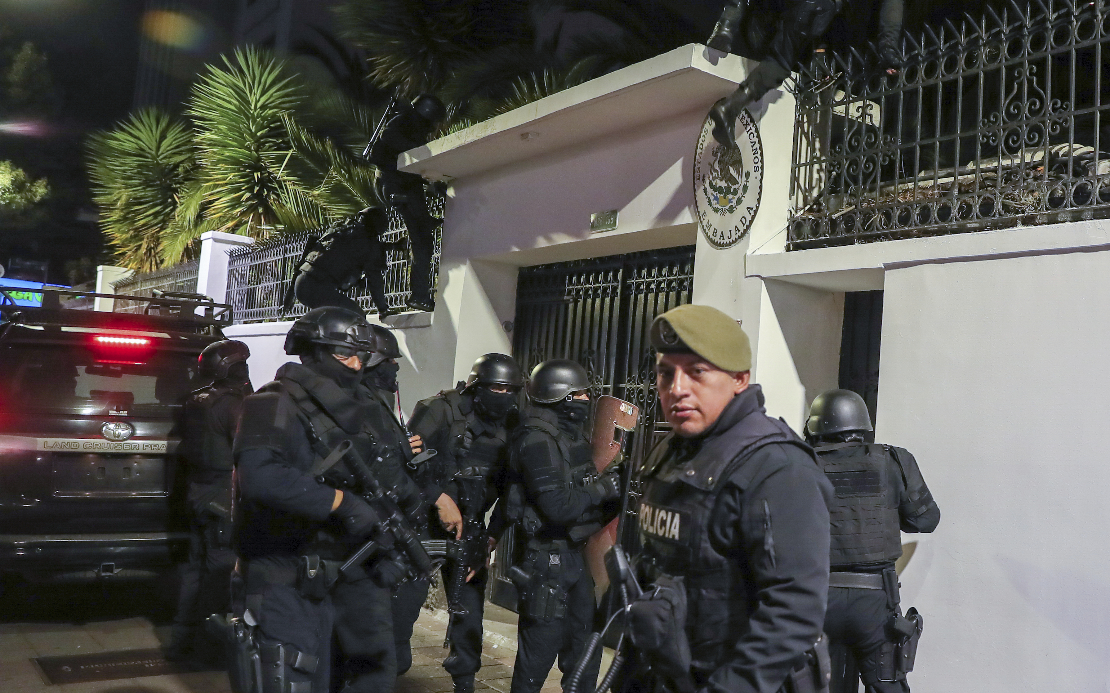 Police gather outside the white concrete gate of the Mexican embassy in Quito.