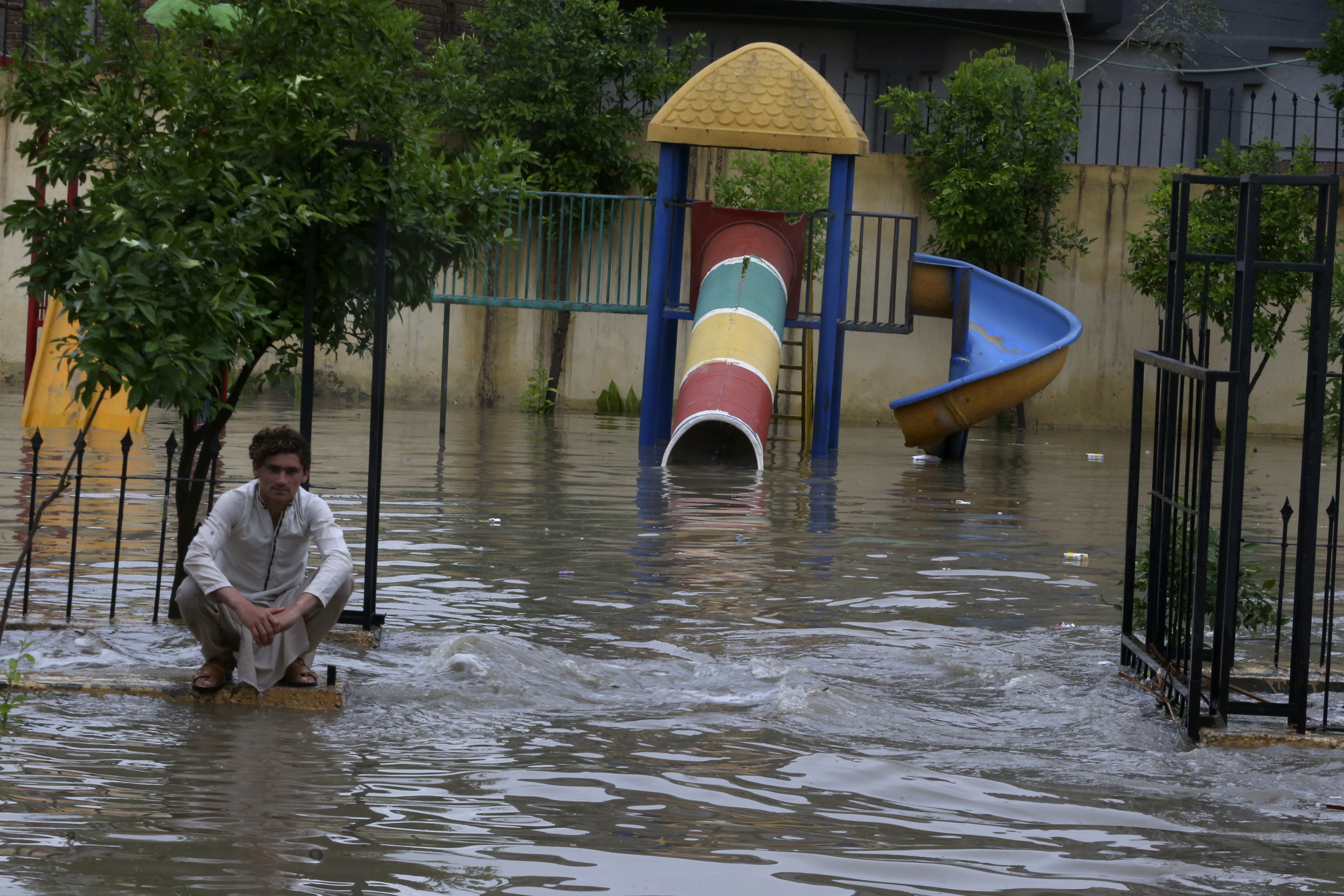 A man sits in a flooded park caused by heavy rain in Peshawar, Pakistan, on April 15
