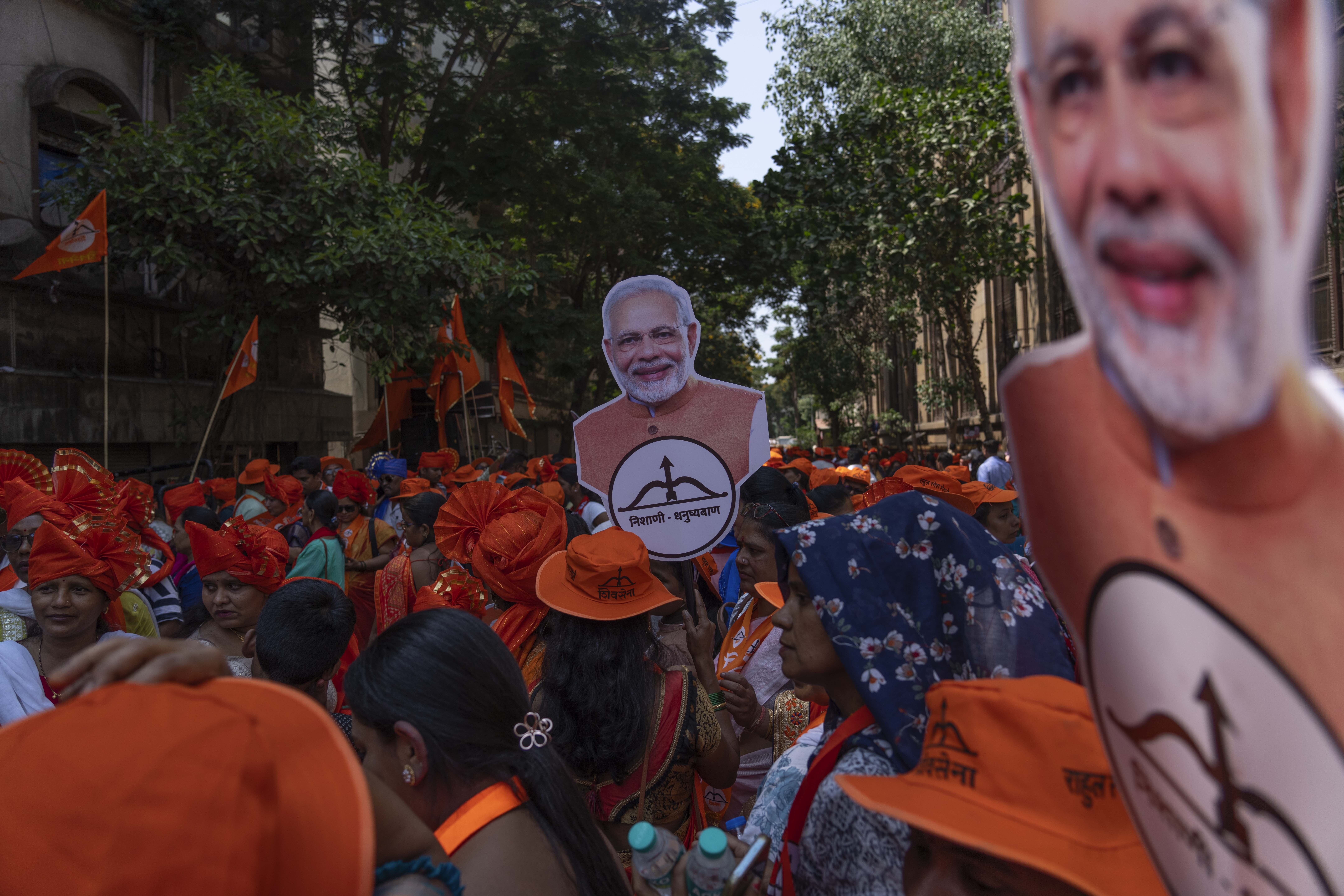 Supporters of National Democratic Alliance walk in a road show holding cutout photos of Indian Prime Minister Narendra Modi as their candidates arrive to file nomination papers ahead of national elections in Mumbai, India, Monday, April 29, 2024. (AP Photo/Rafiq Maqbool)