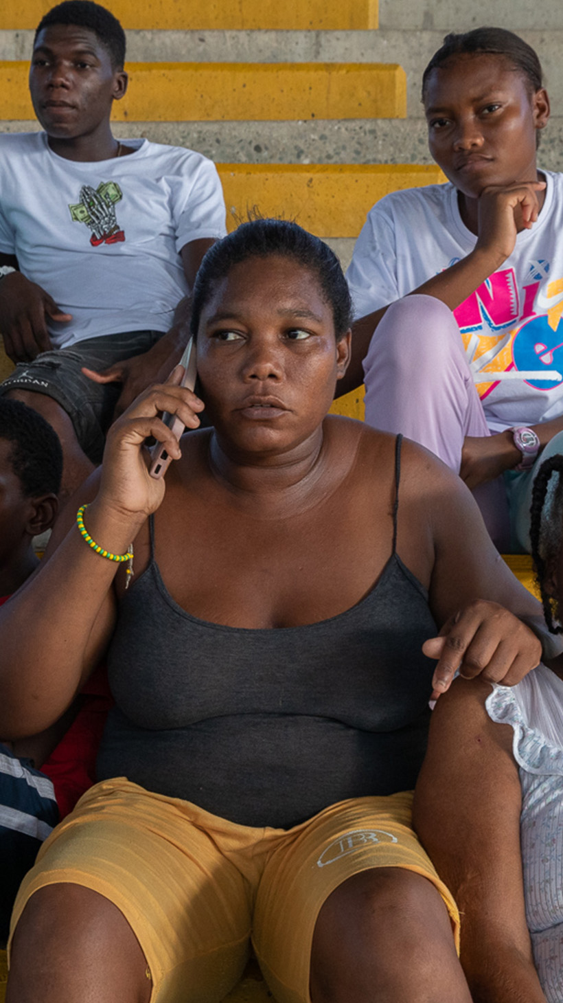 Consuelo Manyoma sits on concrete bleachers surrounded by her children and mother.