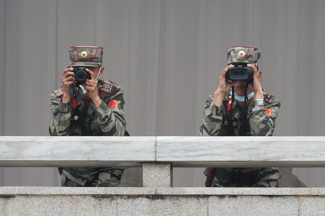 Two North Korean soldiers looking through binoculars at the border