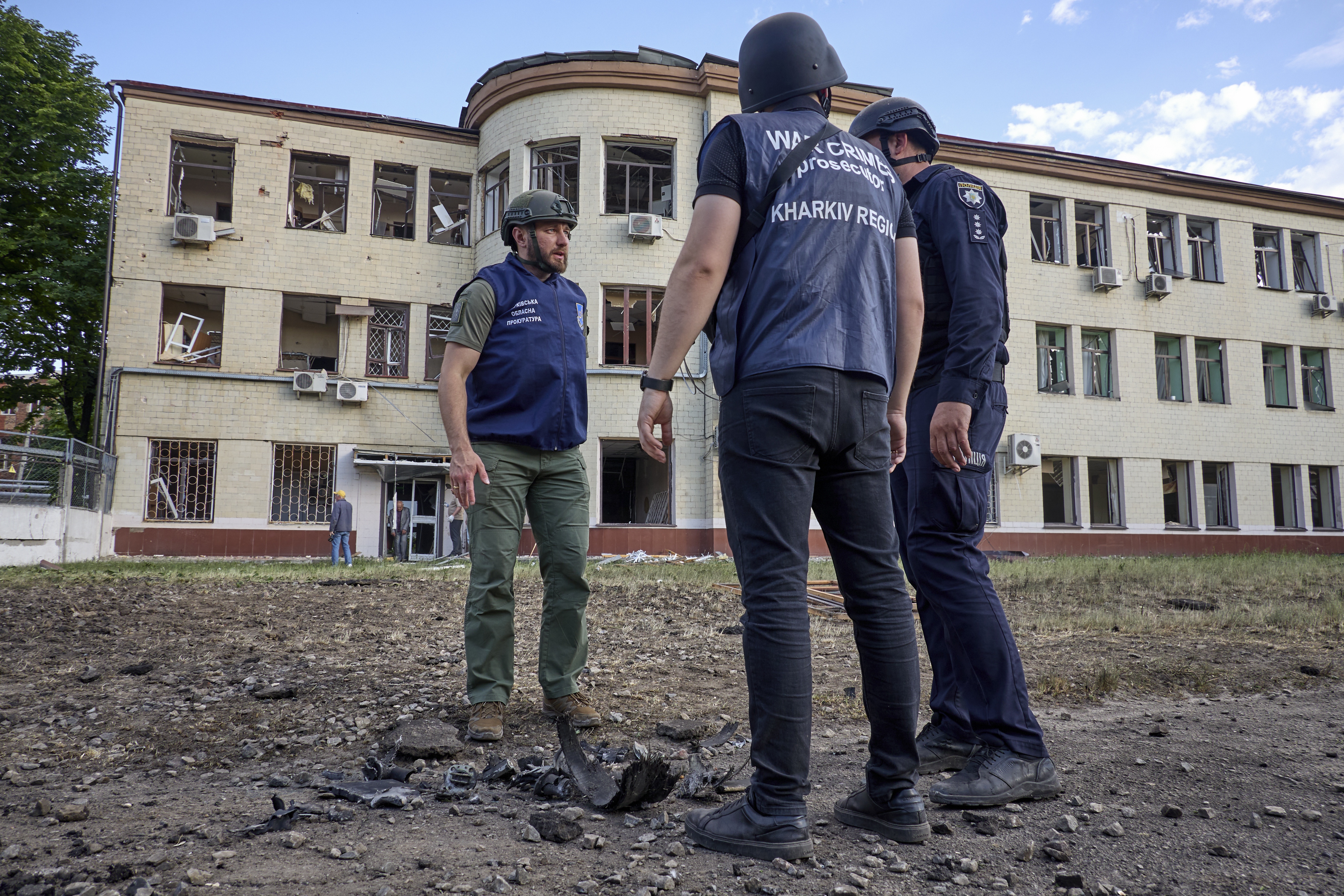 Ukrainian police outside the damaged sweet factory in Kharkiv, Windows have been blown out and there's debris on the ground.