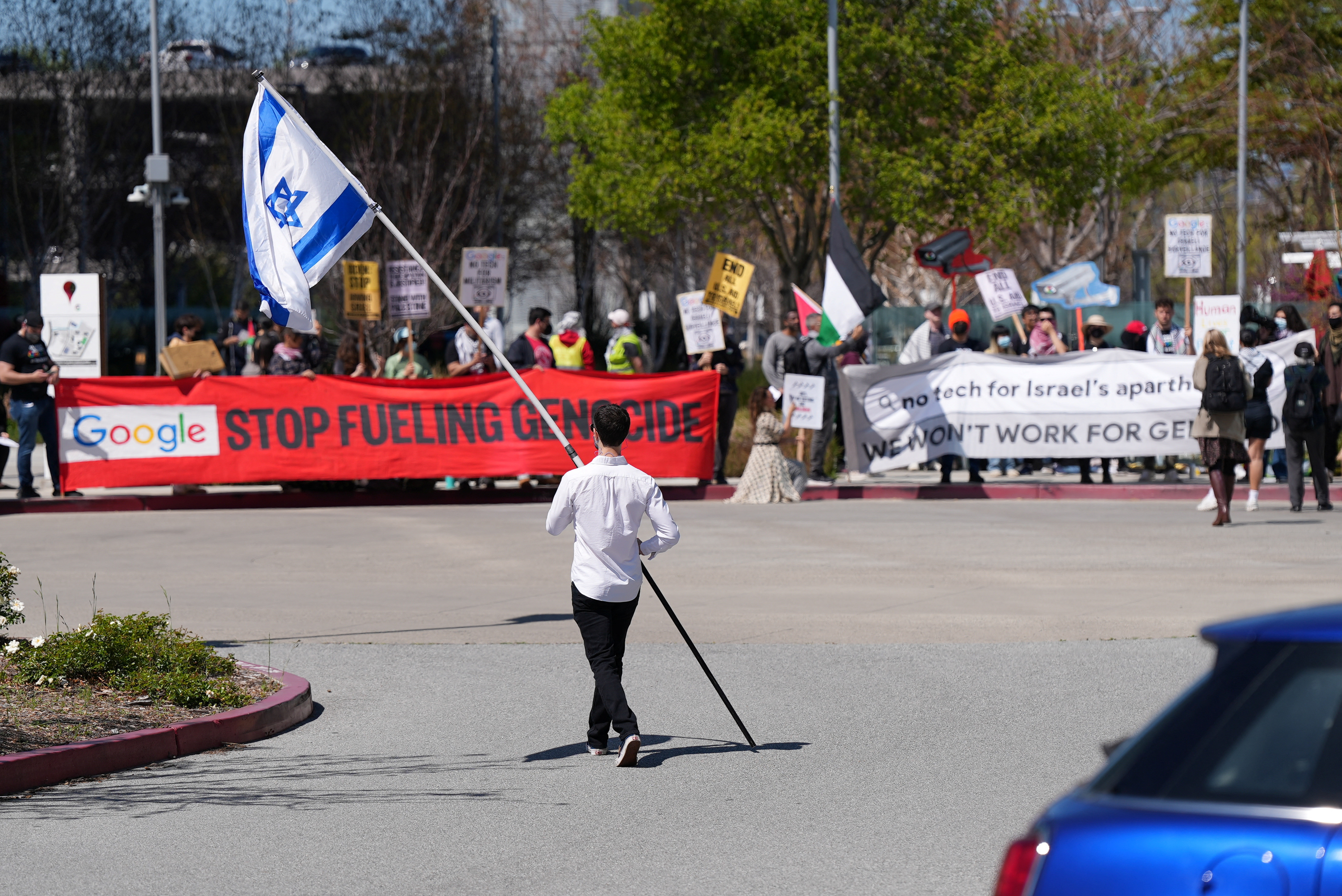 A counter-protester holding an Israeli flag walks into the parking lot near a protest at Google Cloud offices in Sunnyvale, California, U.S. on April 16, 2024. REUTERS/Nathan Frandino