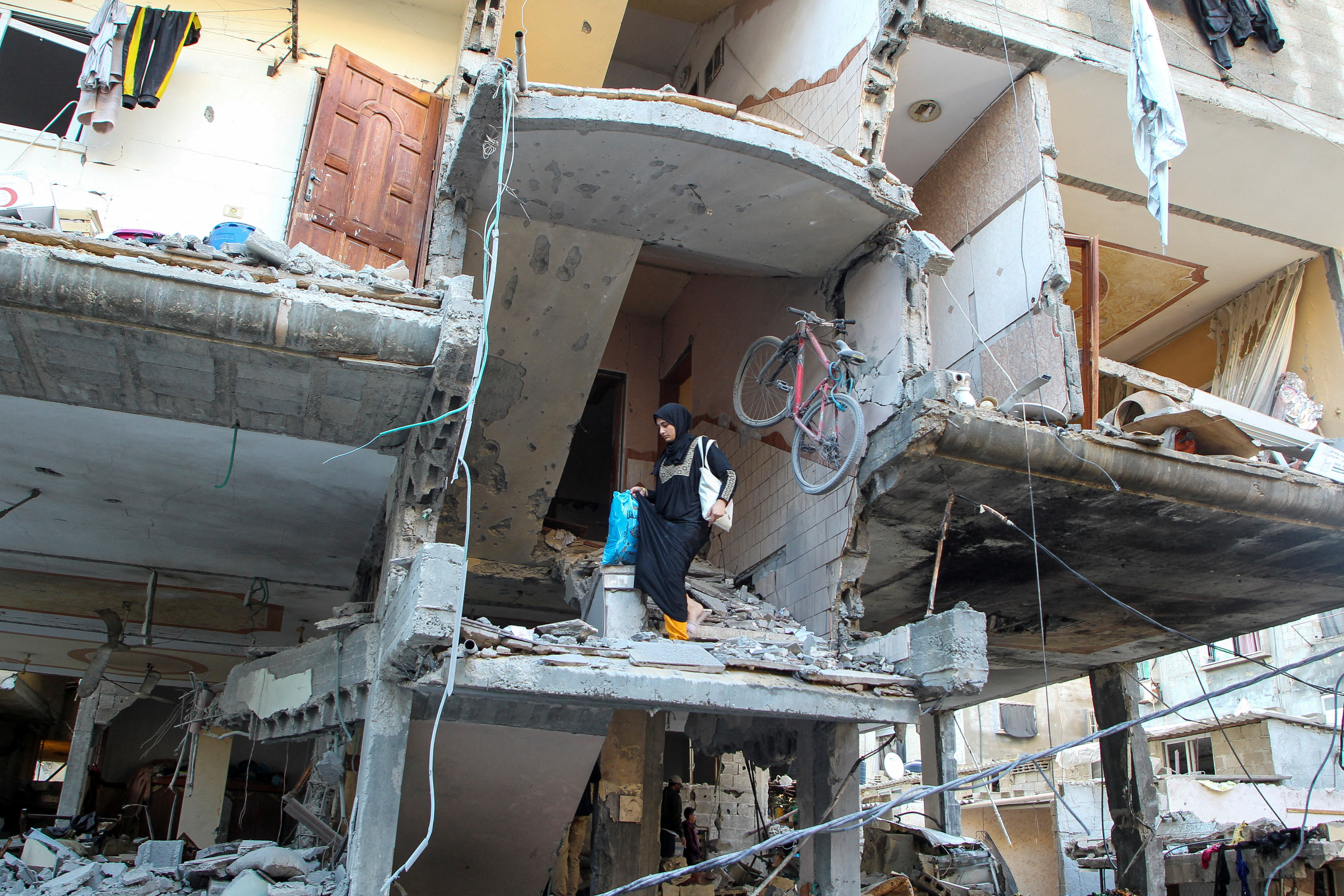 A Palestinian woman walks down the stairs of a house hit in an Israeli strike,