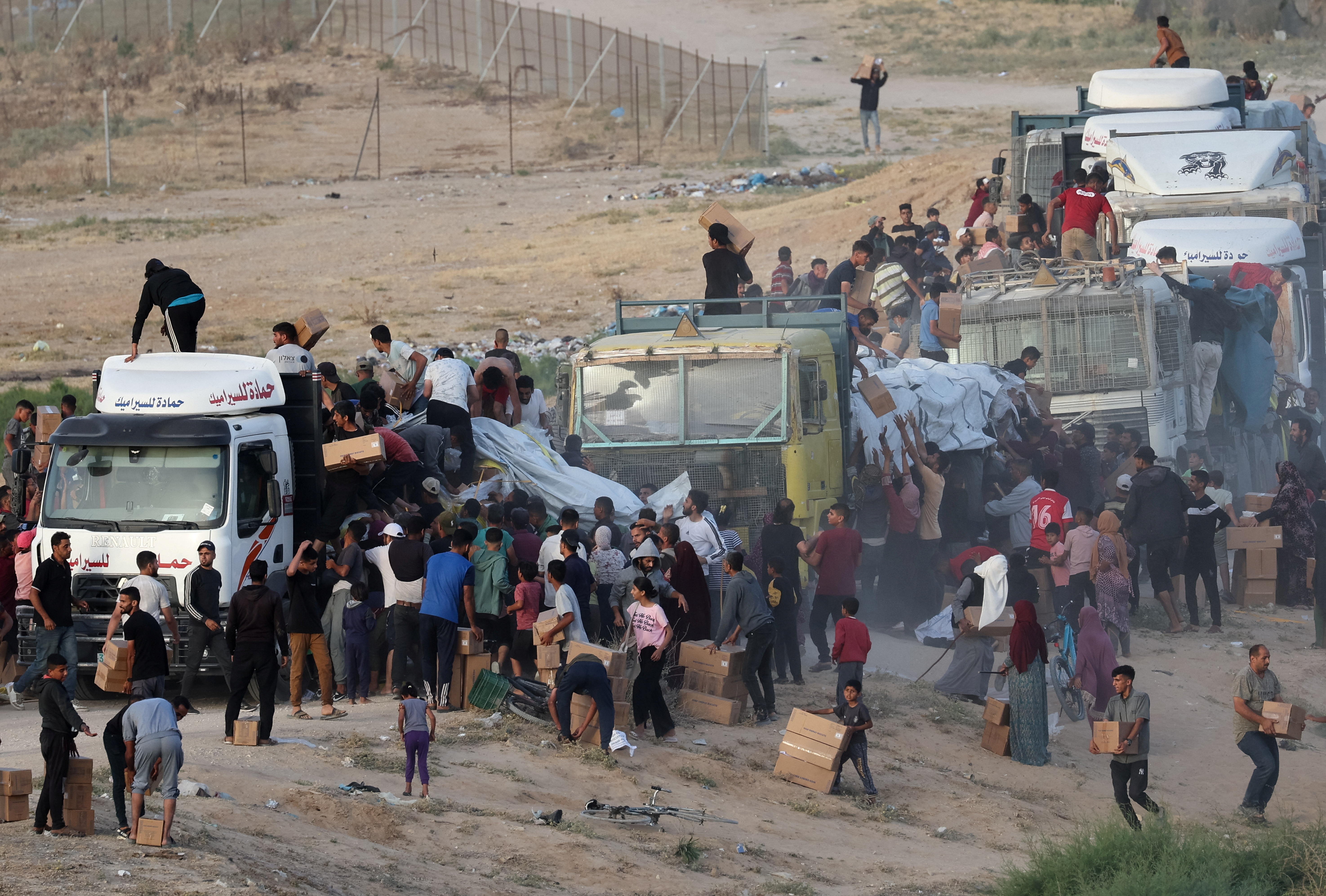 Palestinians climb onto trucks to grab aid that was delivered into Gaza through a U.S.-built pier, as seen from central Gaza Strip, May 18