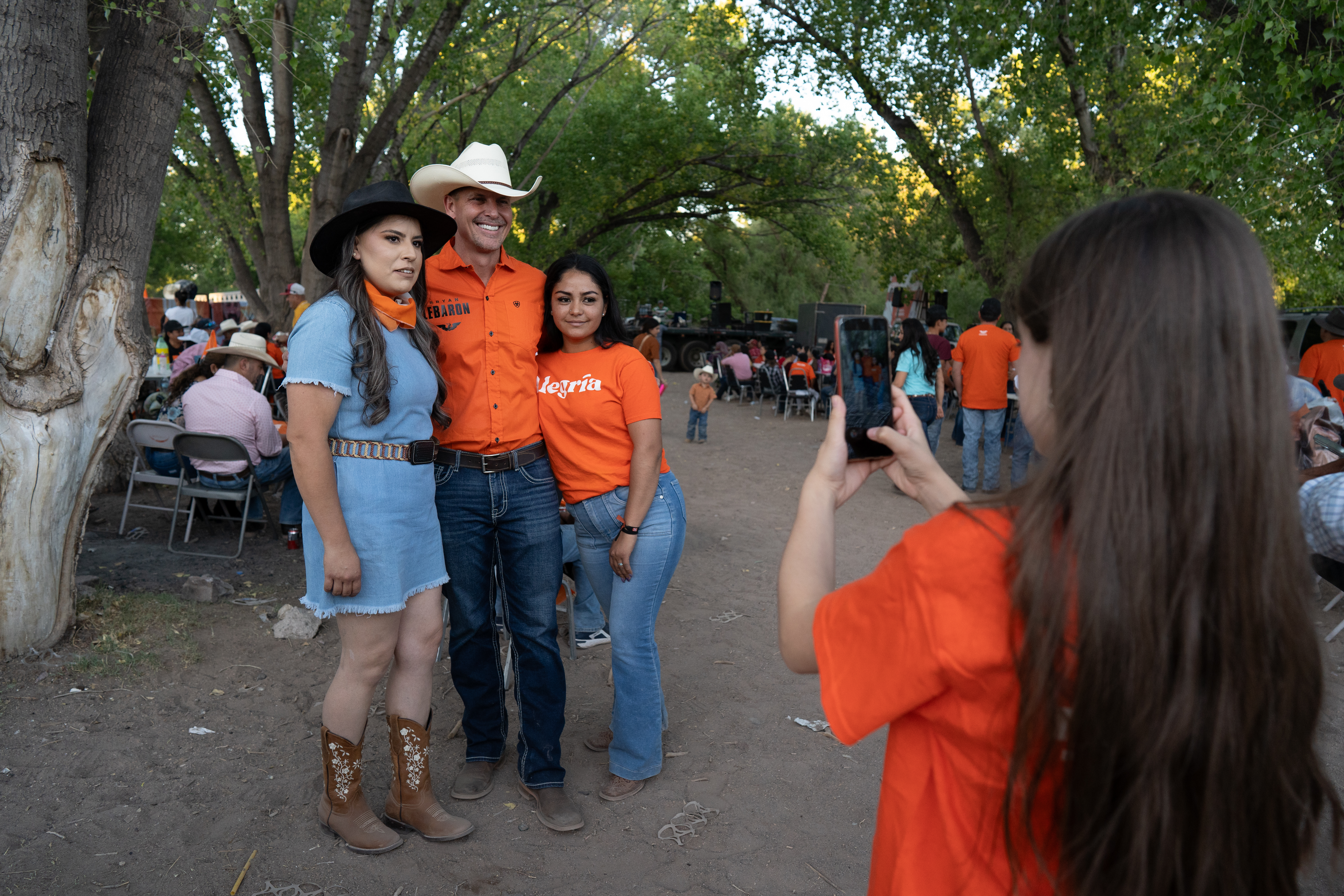 Bryan LeBaron poses with two women as a third takes a photo with her phone.