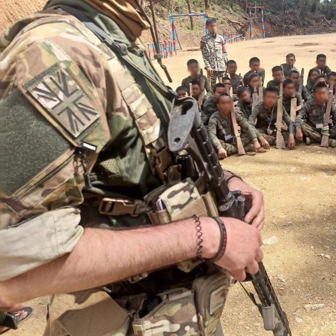 A close up a Union Jack in camouflage colours on the shoulder of a foreign fighter.