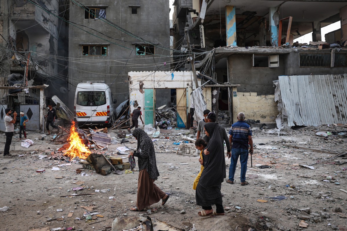 Palestinians look at the rubble of a family house