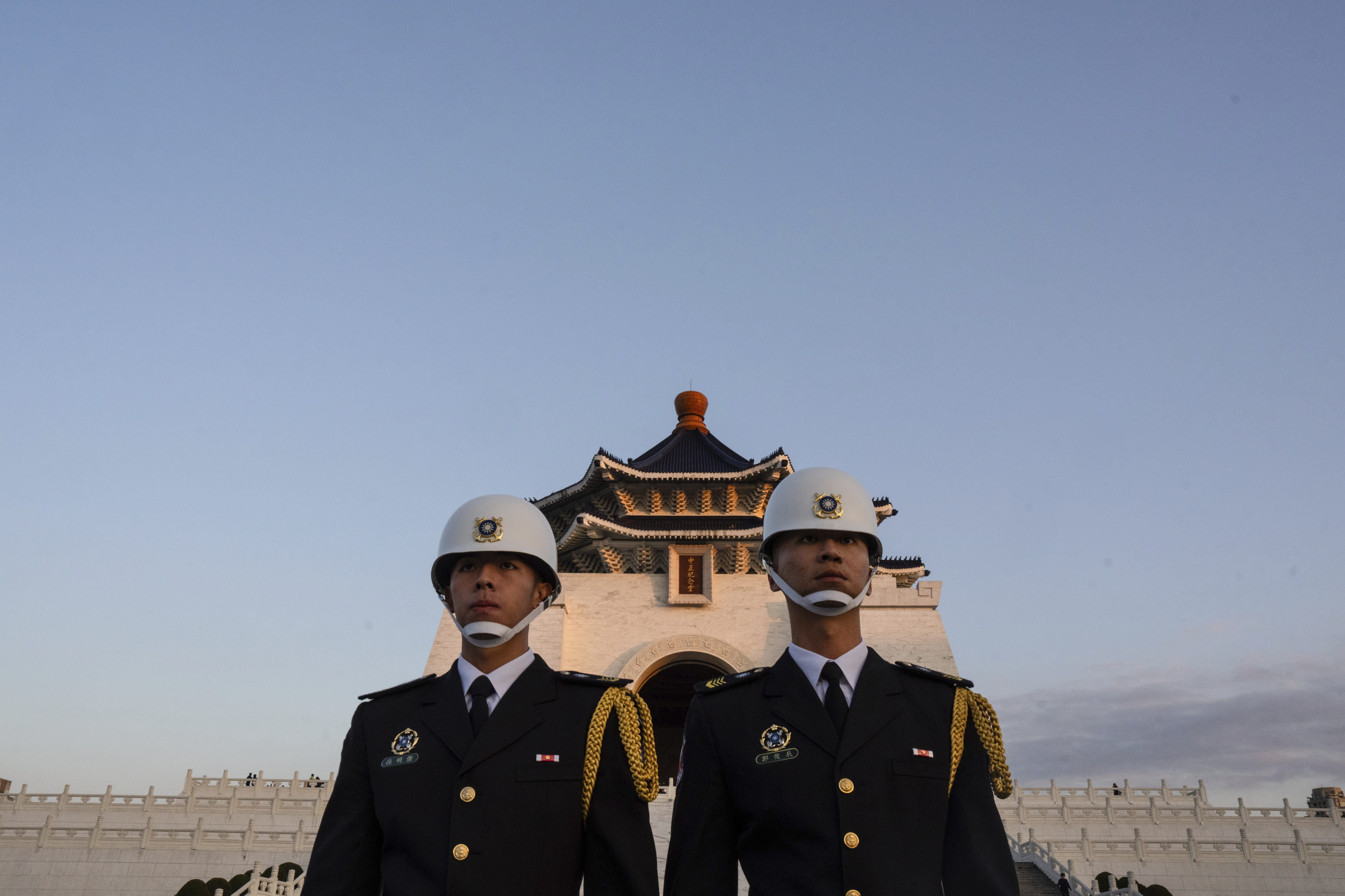 An honour guard in front of the Chiang Kai-shek memorial hall in Taipei. It's disk and the sky is blue.