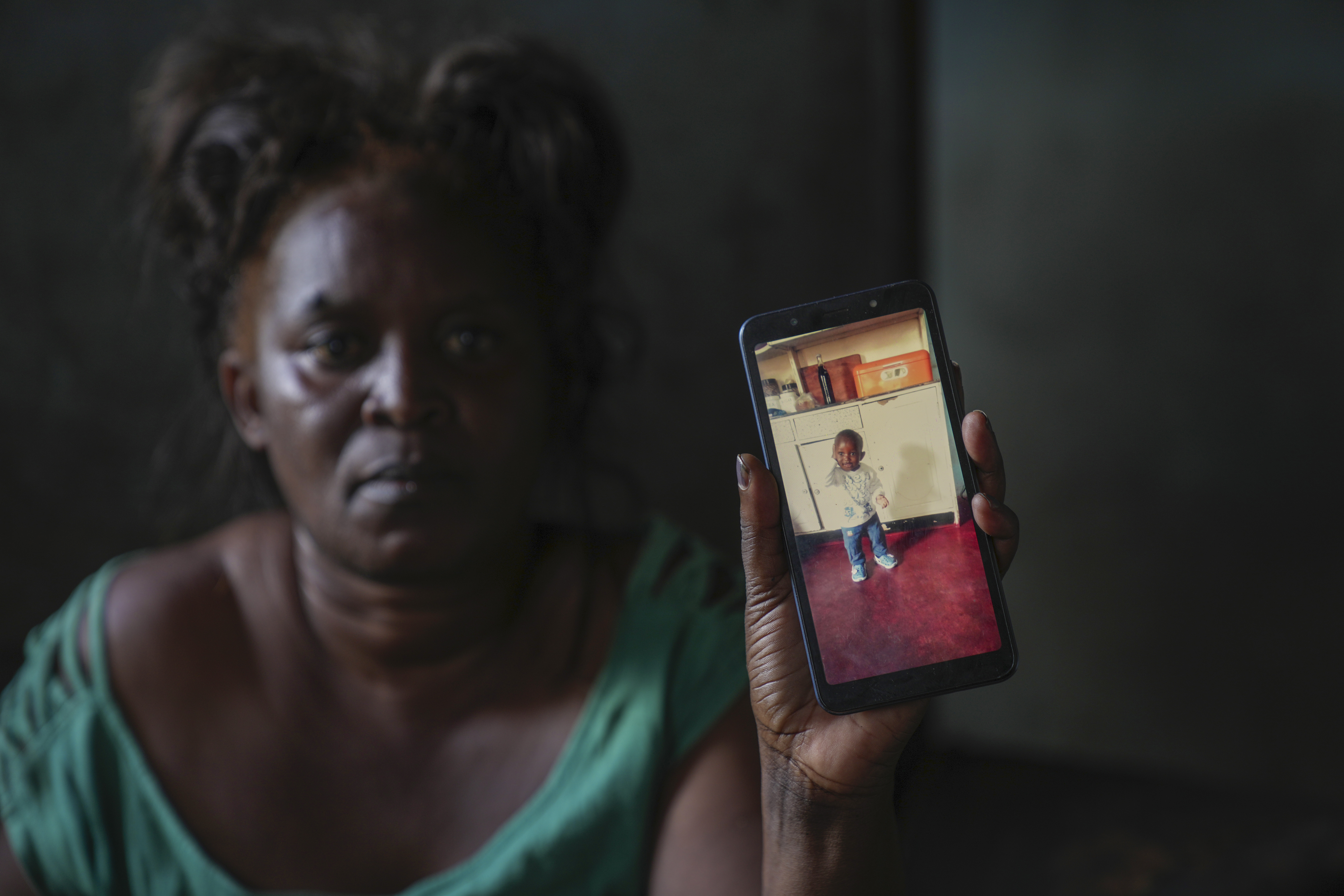 Mildred Banda holds a phone showing a picture of her one-year-old son who died of Cholera in Lilanda township in Lusaka, Zambia,