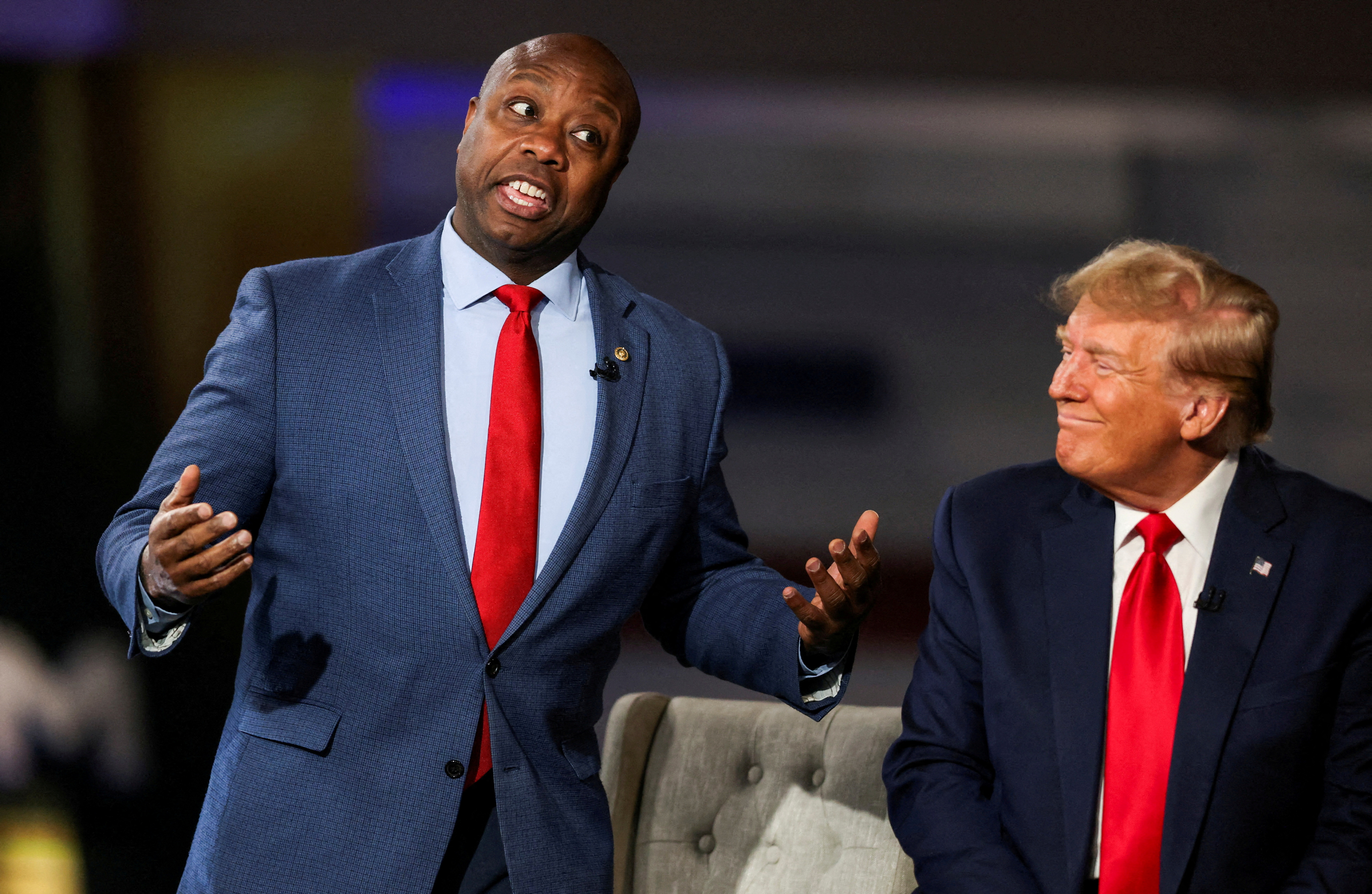 Tim Scott gestures next to Donald Trump