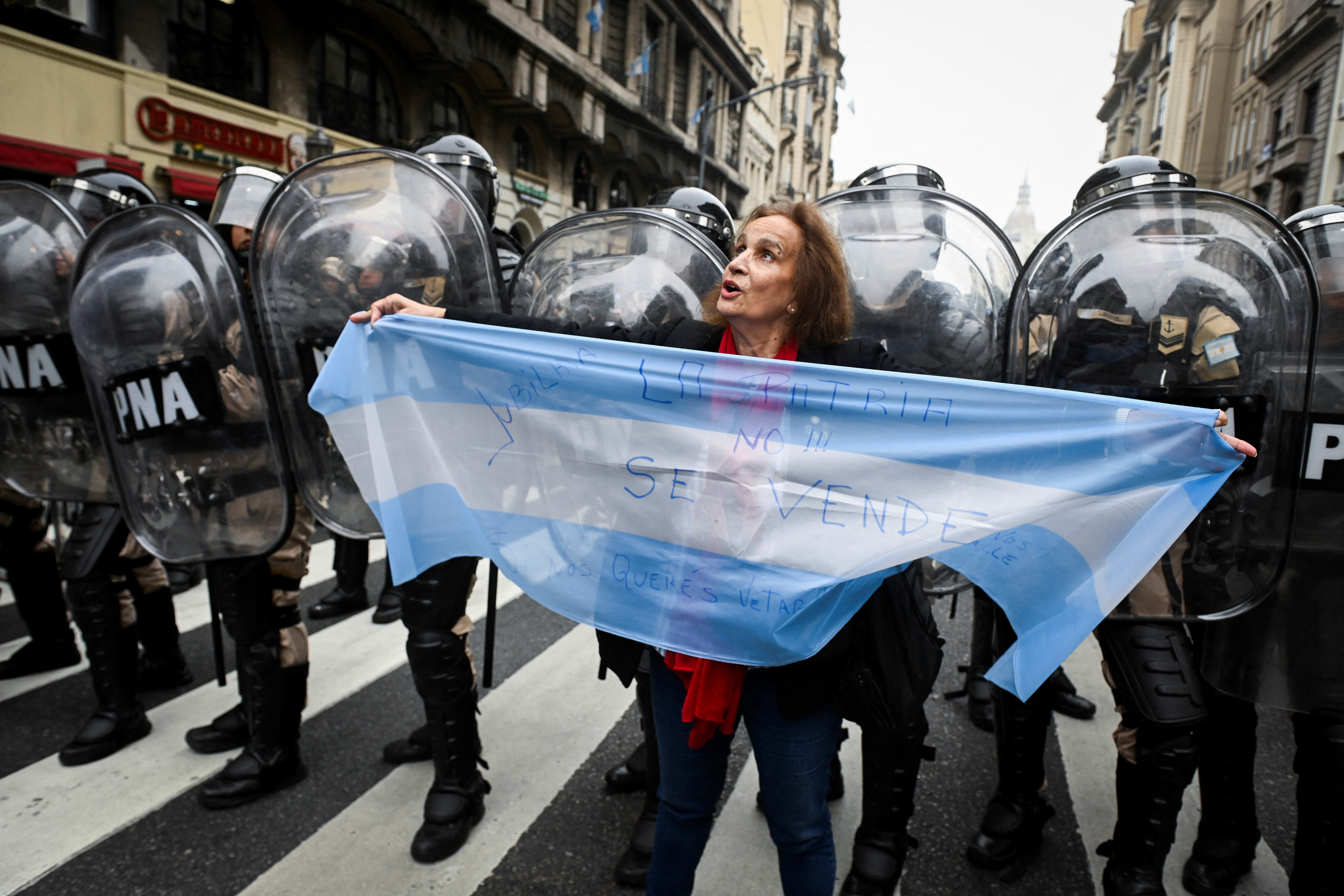 A woman holds an Argentina flag in front of a row of riot police in Buenos Aires.