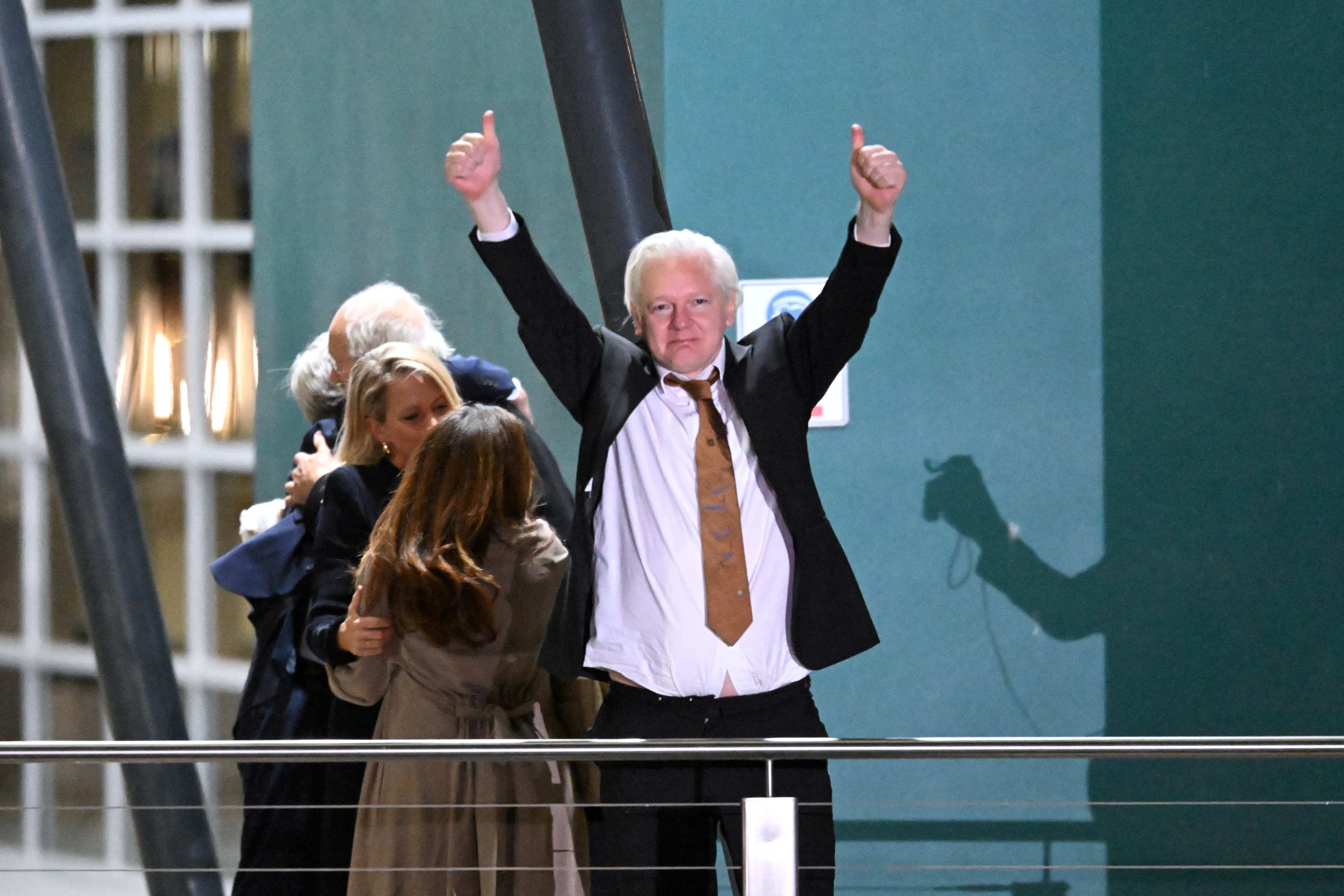 WikiLeaks founder Julian Assange gestures at supporters after arriving at Canberra Airport