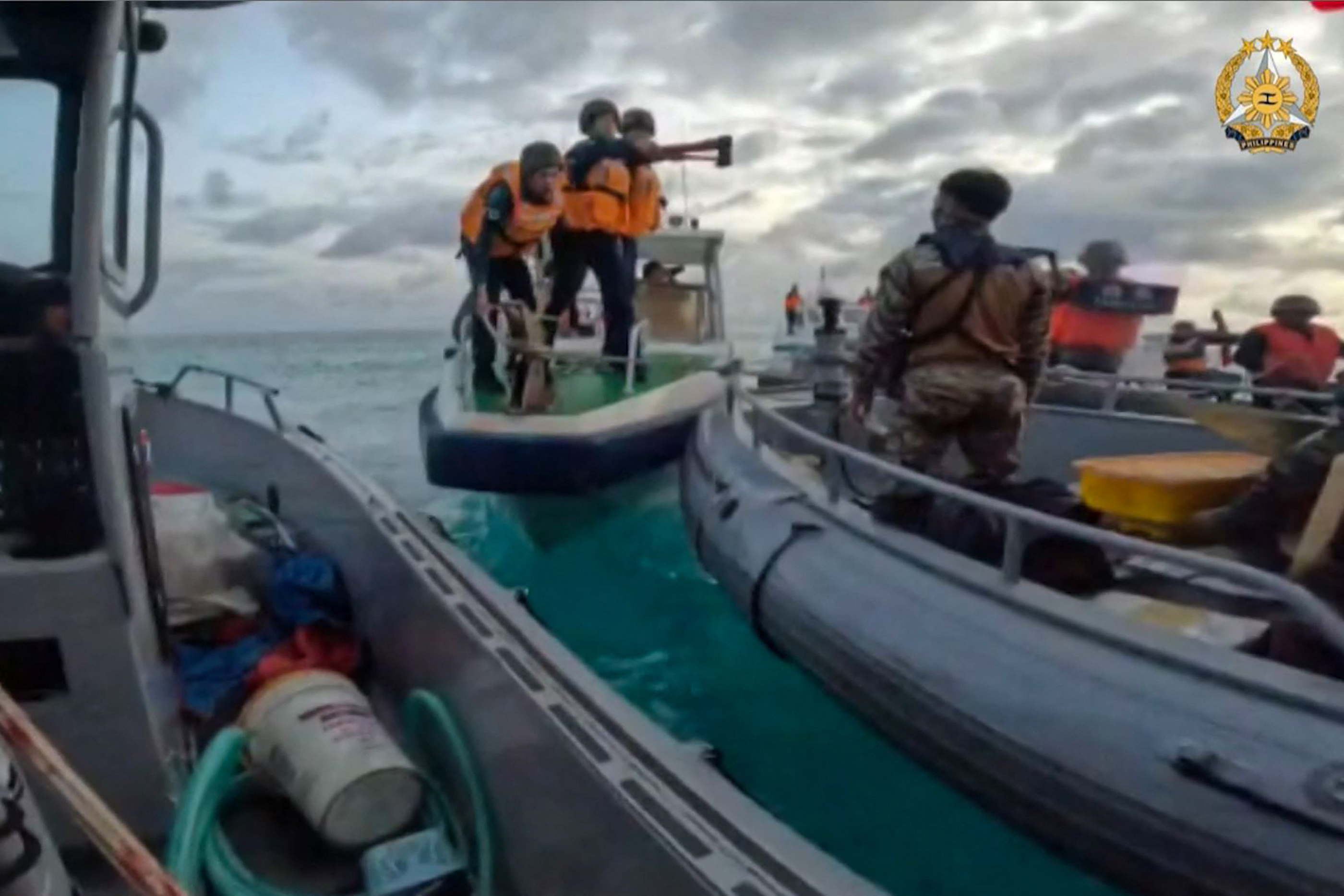 Chinese vessels surrounding a Philippines resupply mission in the South China Sea. There are mutiple Coast Guard personnel. One appears to have an axe.