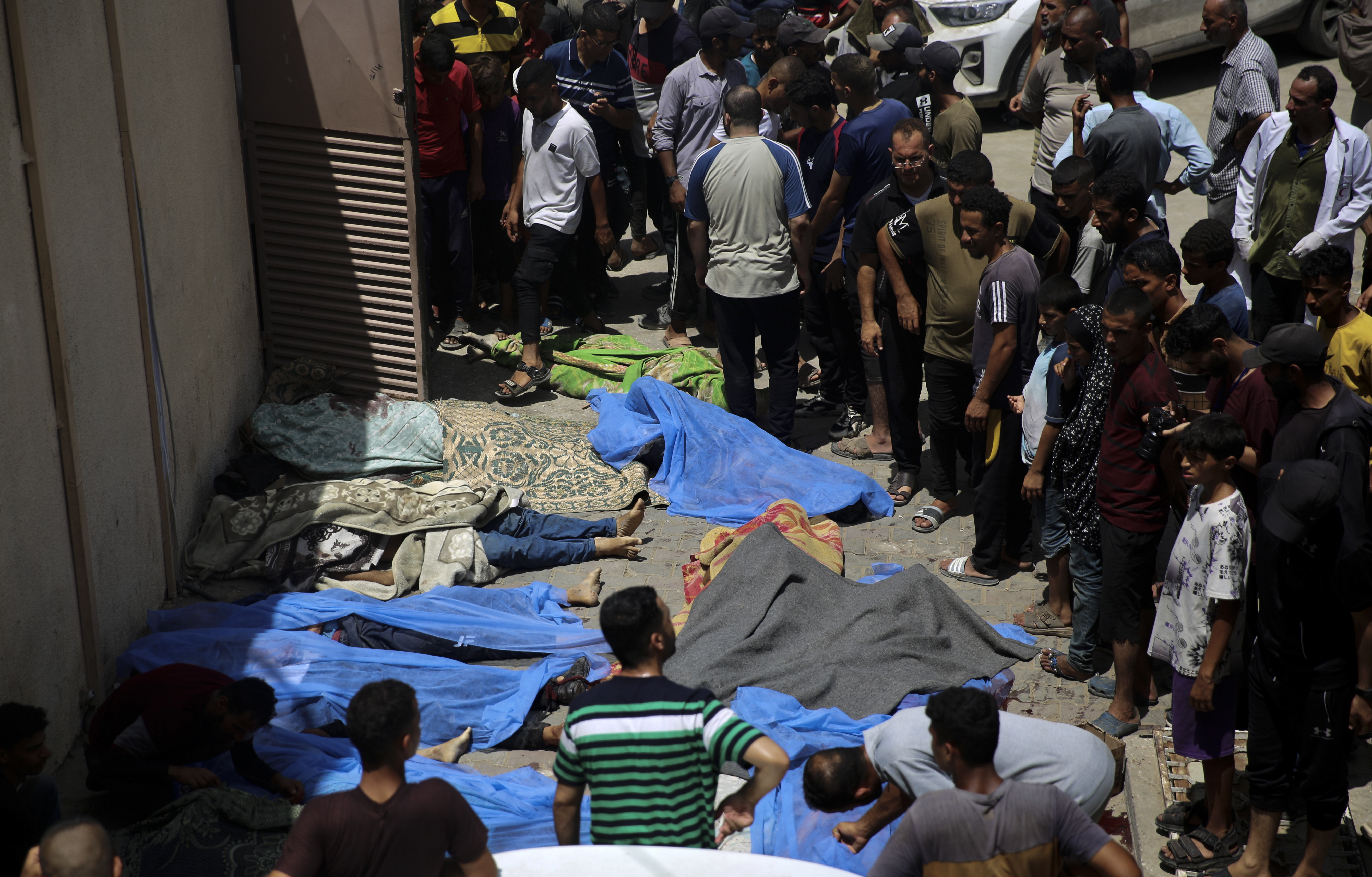 Palestinians stand by their relatives killed in the Israeli bombardment of the Gaza Strip at al-Aqsa Hospital in Deir al Balah on Saturday, June 8