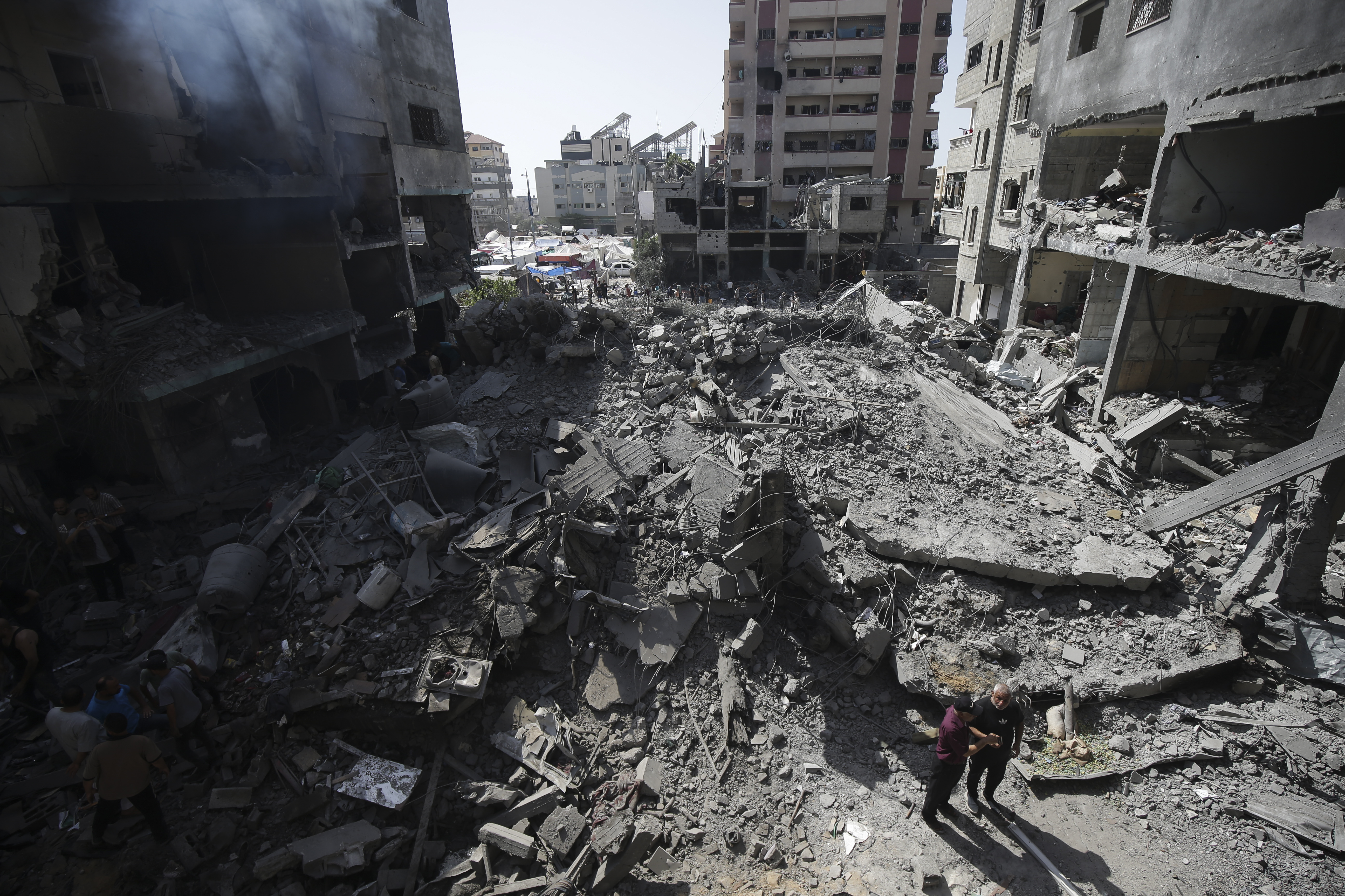 Palestinians look at the aftermath of the Israeli bombing in Nuseirat refugee camp, Gaza Strip, Saturday, June 8