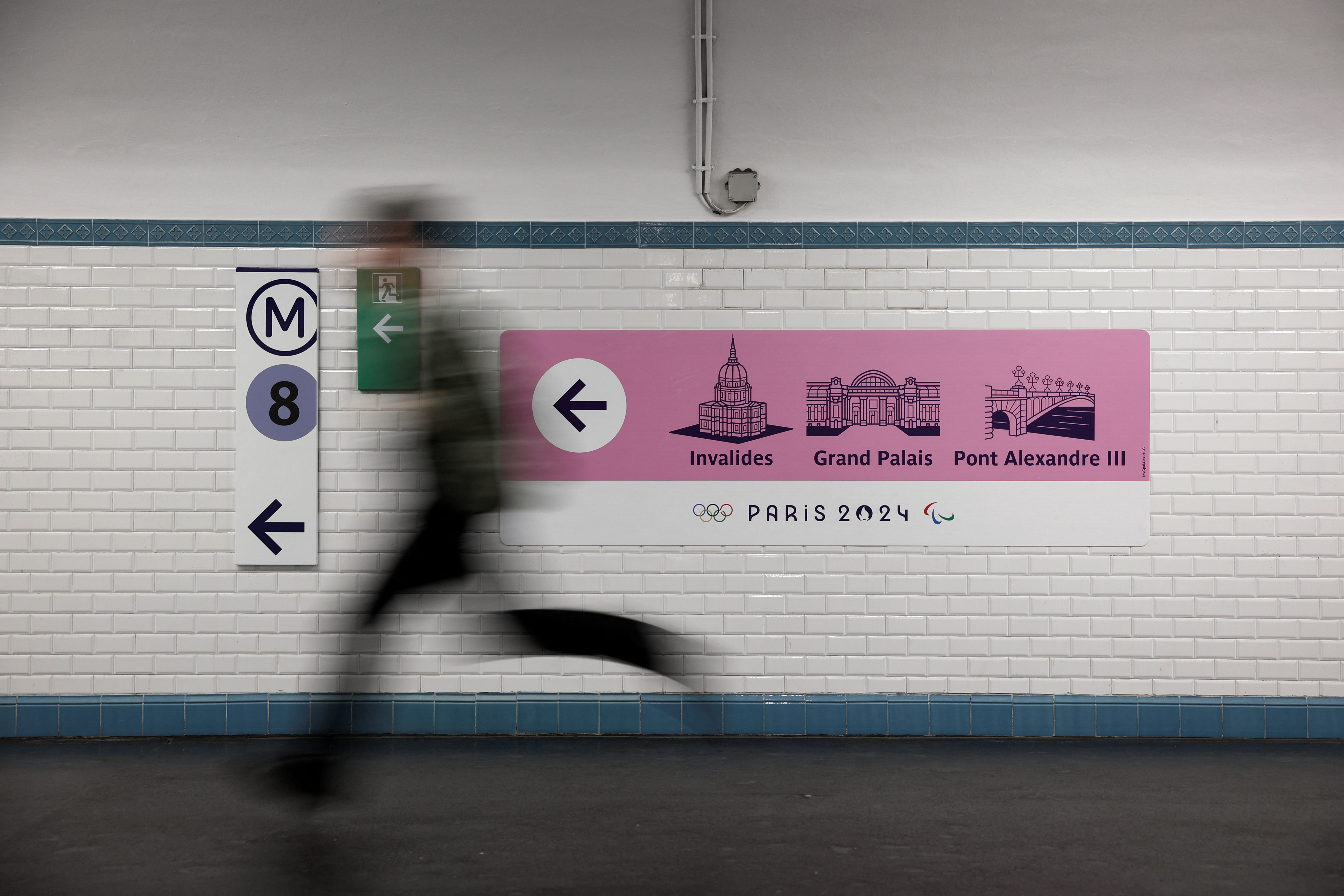 Man runs past Paris Metro station.