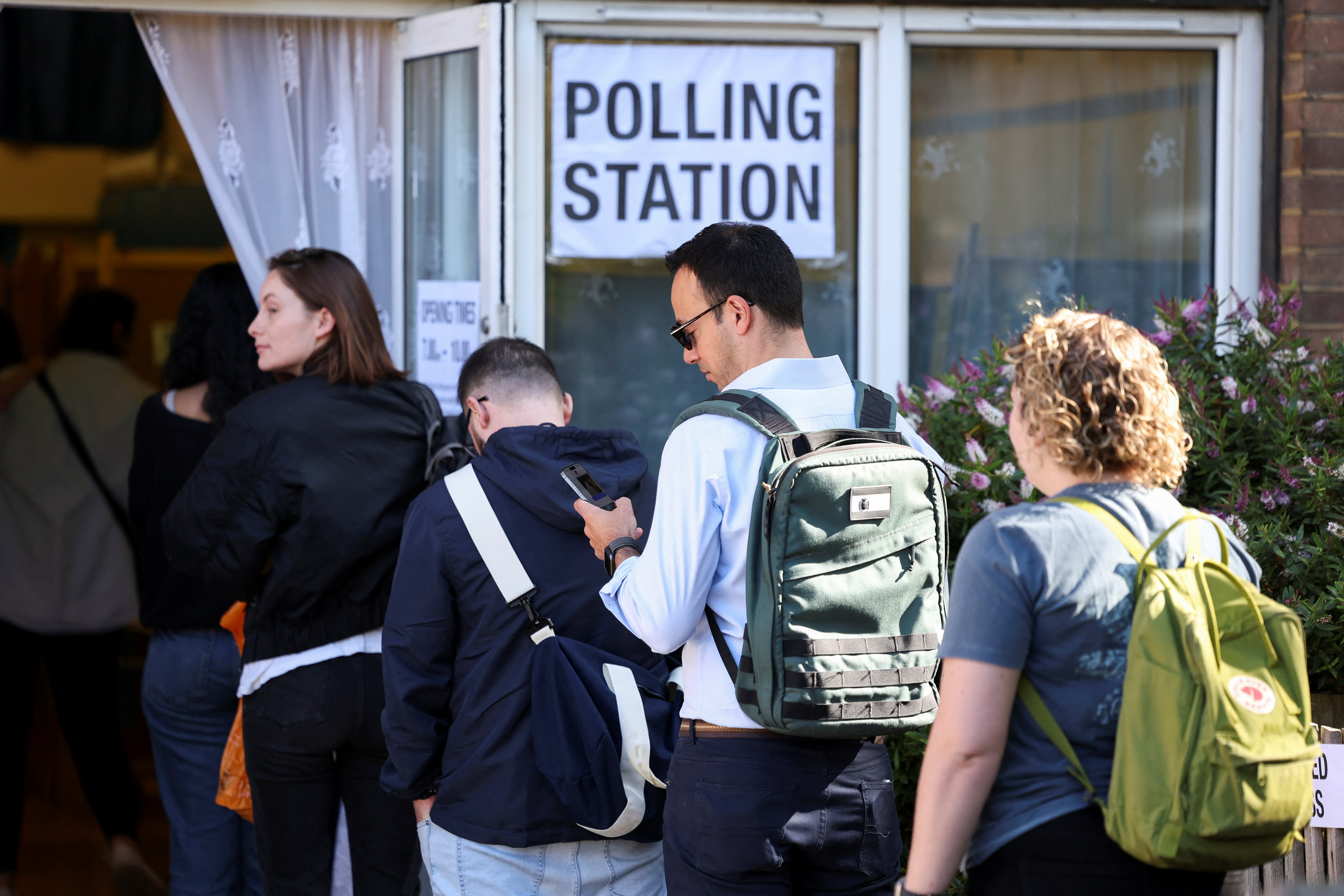 People queue to vote at a polling station during the general election in London, Britain