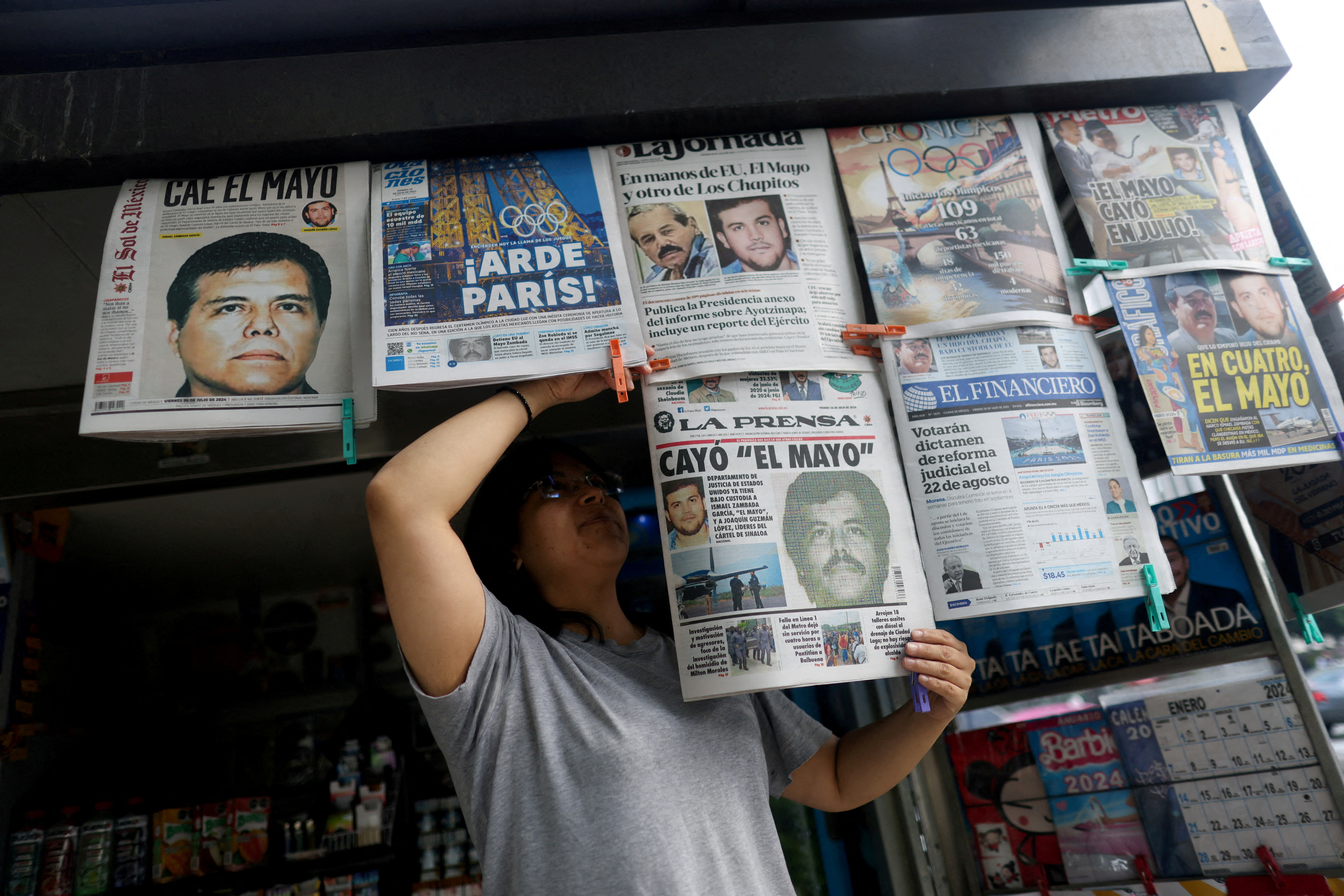 A newspaper seller arranges newspapers reporting the El Paso, Texas, U.S., arrest of Mexican drug lord Ismael "El Mayo" Zambada and Joaquin Guzman Lopez, "El Chapo" Guzman's son