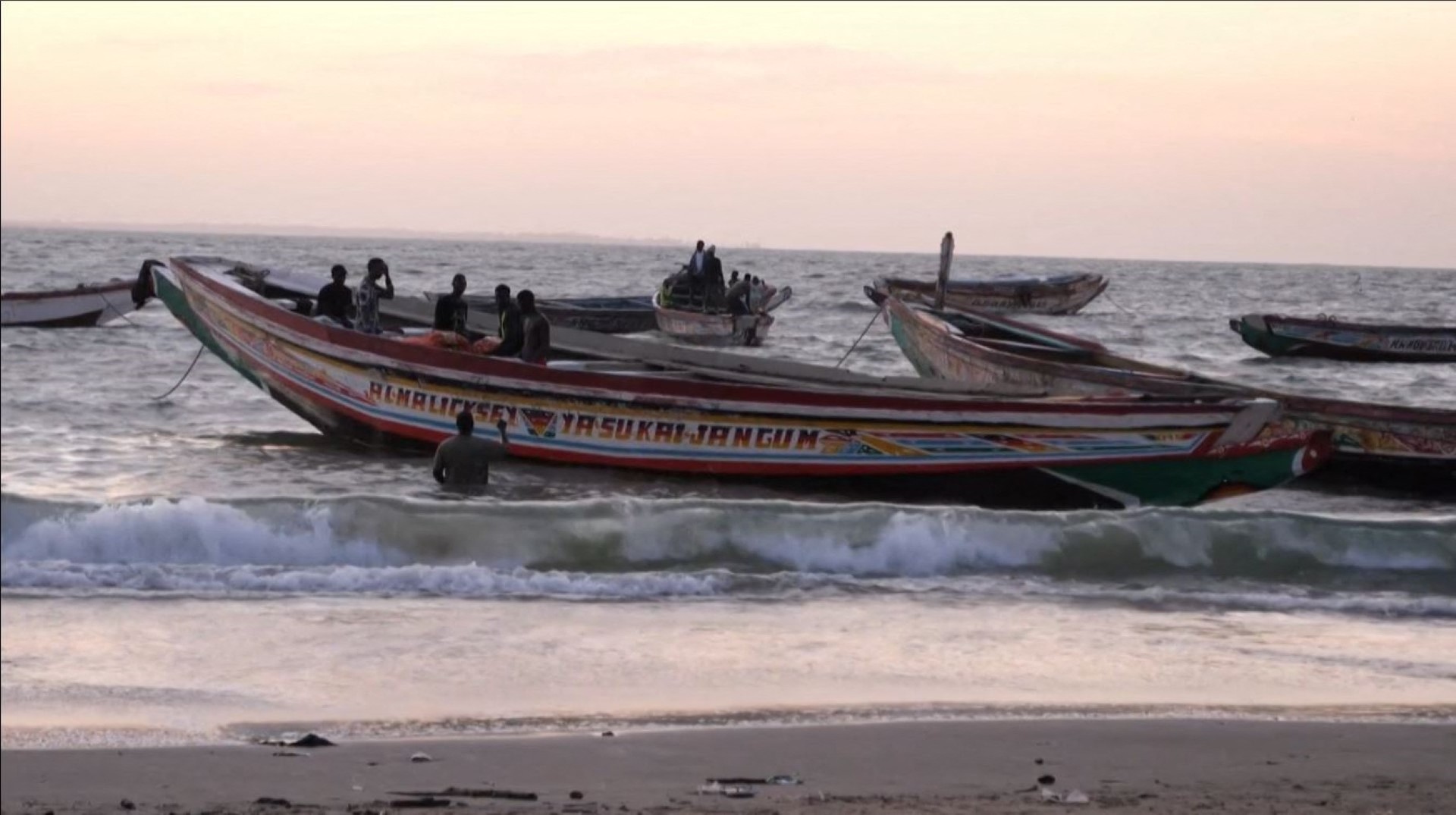 Boats in the water at a beach, in Barra on December 5, 2019, after at least 62 people died on December 4, 2019 when their makeshift vessel capsized off the coast of Mauritania