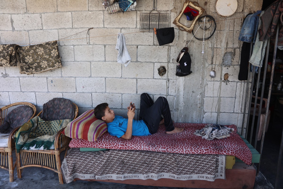 A Palestinian boy checks his smart phone while resting at home in the Sheikh Radwan