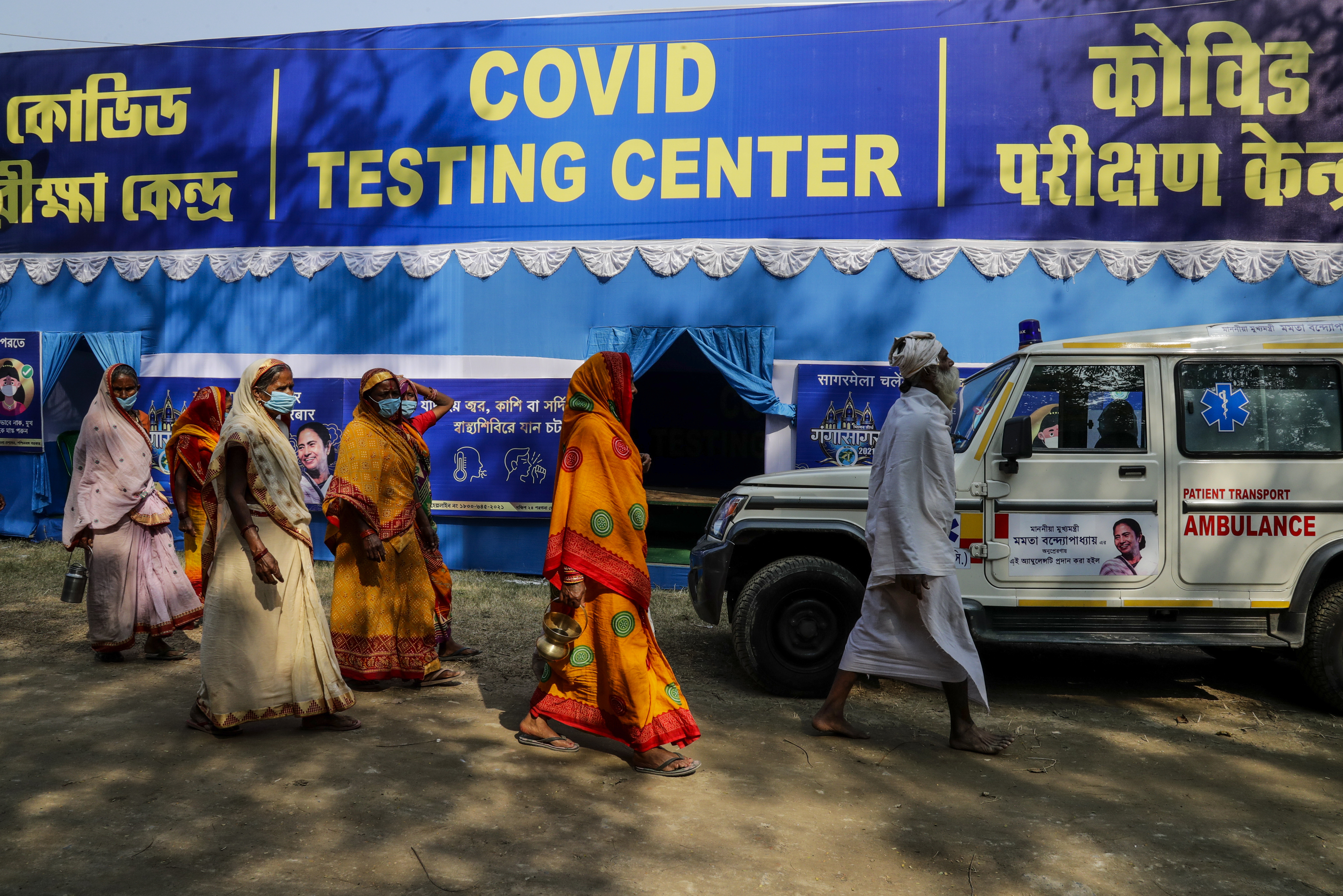 A group of Hindu pilgrim headed for the Gangasagar pilgrimage walk past a temporary COVID-19 testing camp at a transit camp in Kolkata, India, Sunday, Jan. 10, 2021. This year due to the pandemic, authorities are anticipating less number of pilgrims during the annual pilgrimage that coincides with the Makar Sankranti festival that falls on Jan. 14. (AP Photo/Bikas Das)