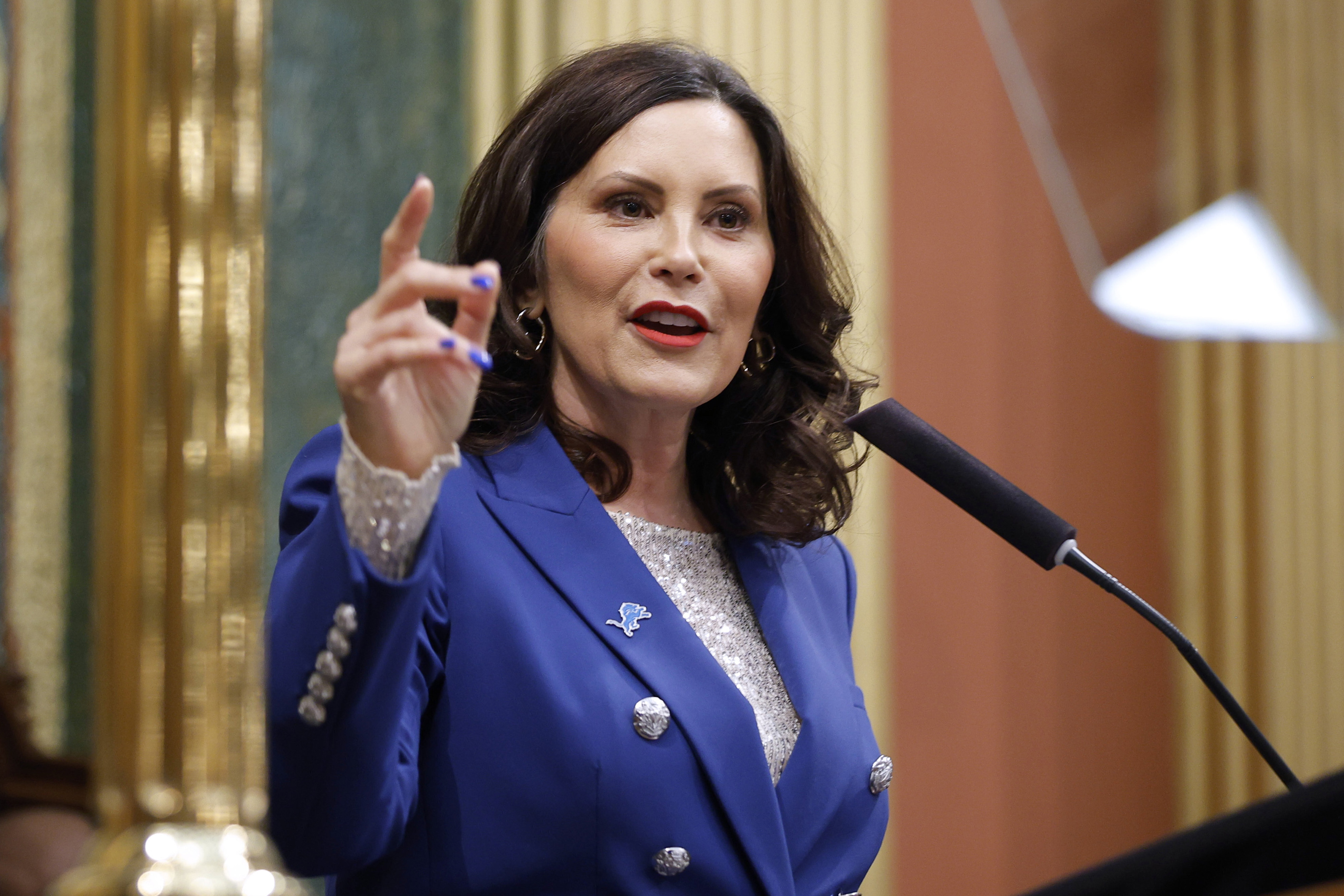 Gretchen Whitmer points while speaking at a podium.