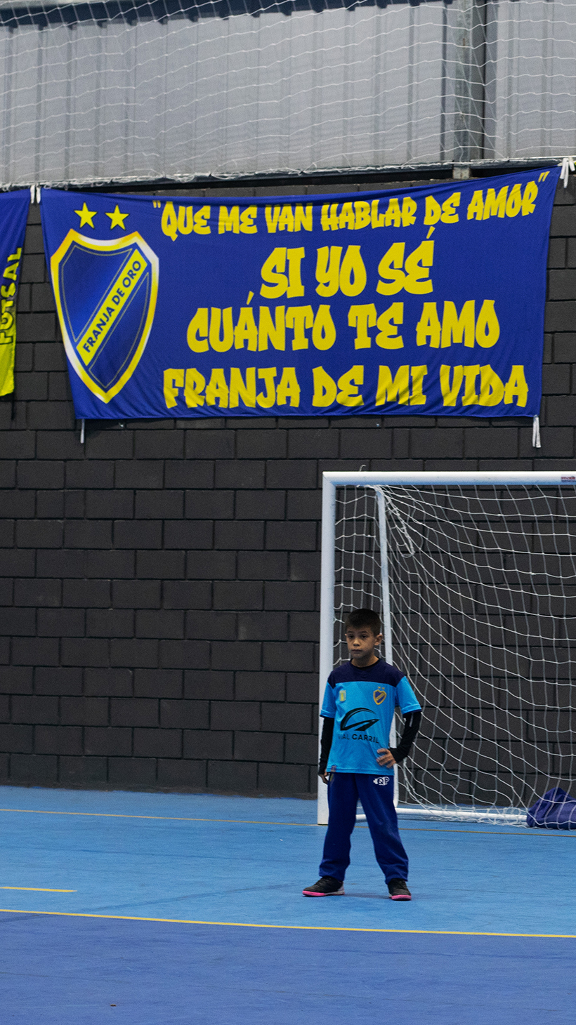 A child stands guard as goalie on an indoor soccer field.