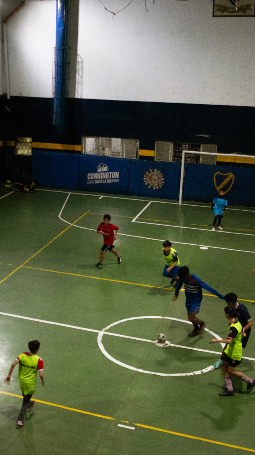 An aerial view of an indoor sports field, where children play soccer.