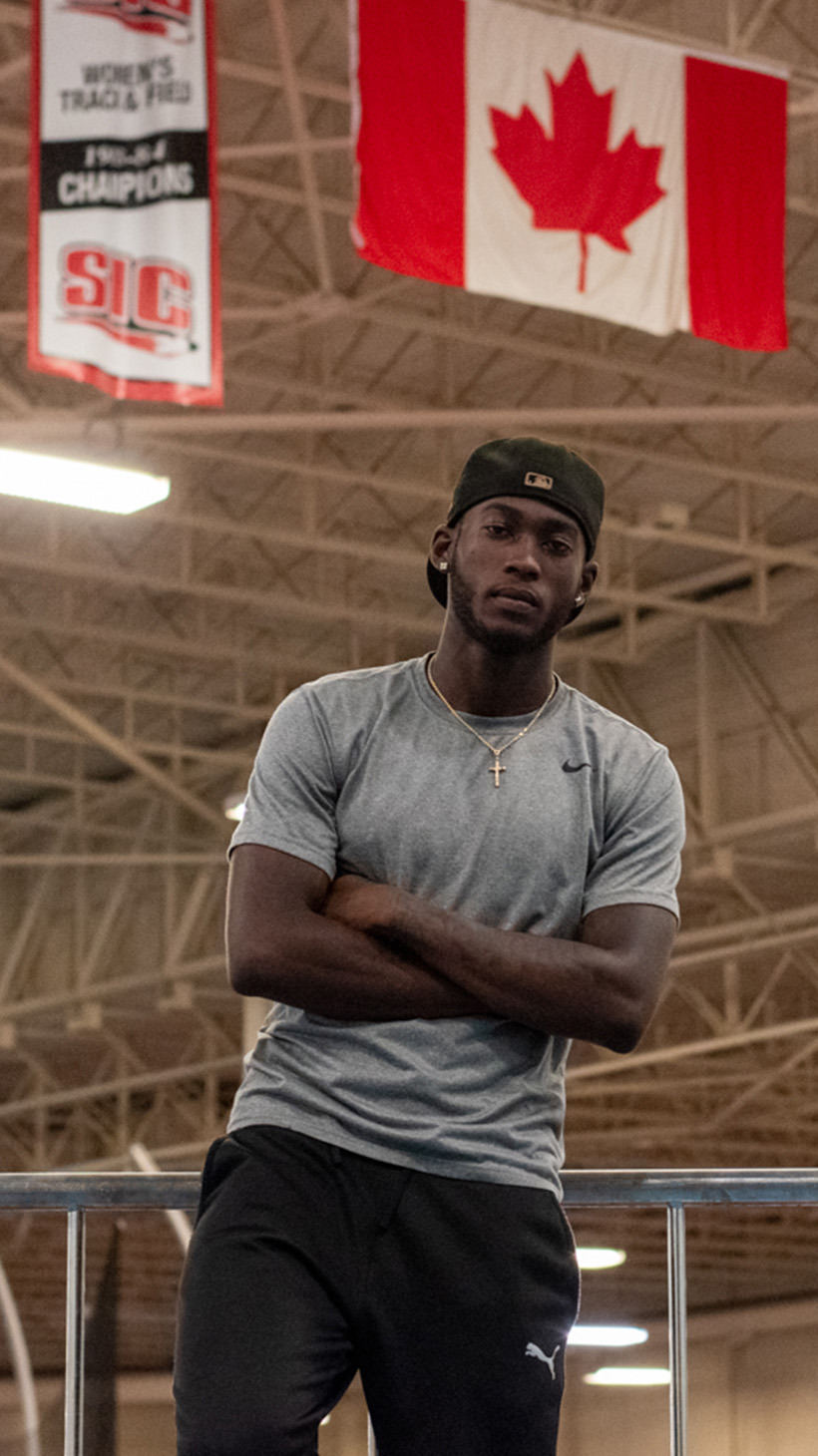 Tamarri Lindo poses under the Canadian flag in an indoor sports arena.