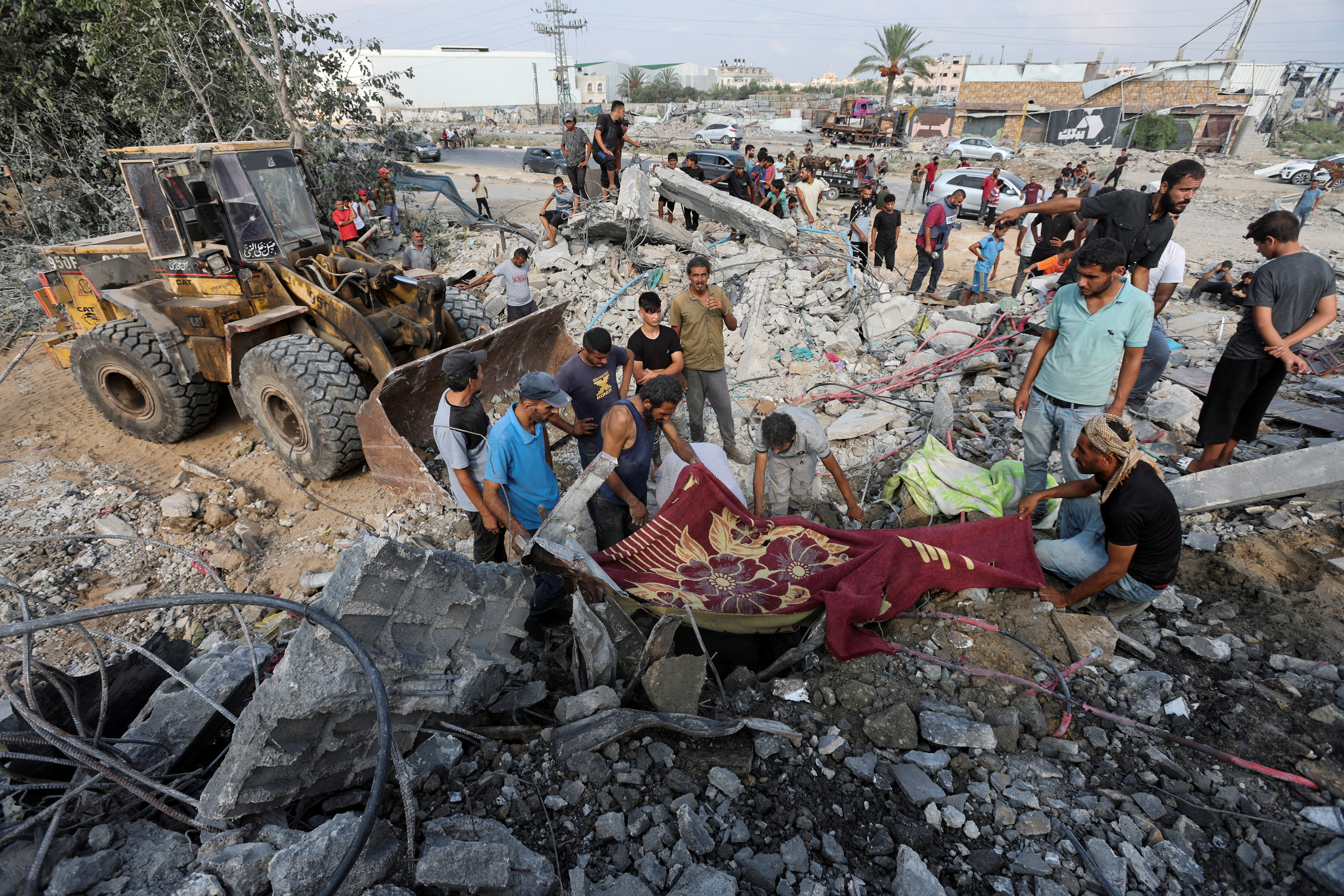 Palestinians stand at the site of an Israeli attack on a building in Gaza